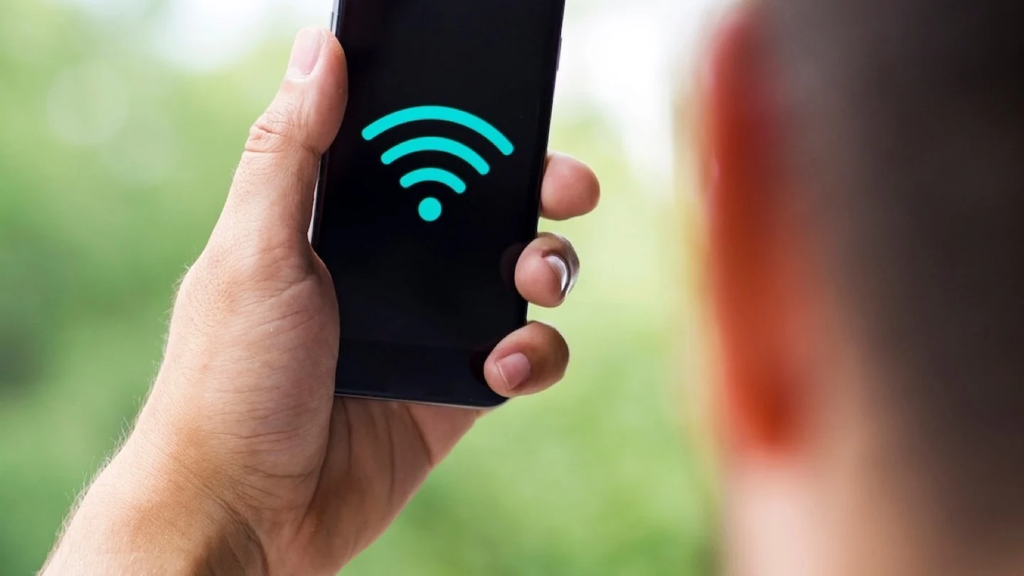 A person holds a smartphone displaying a Wi-Fi symbol.