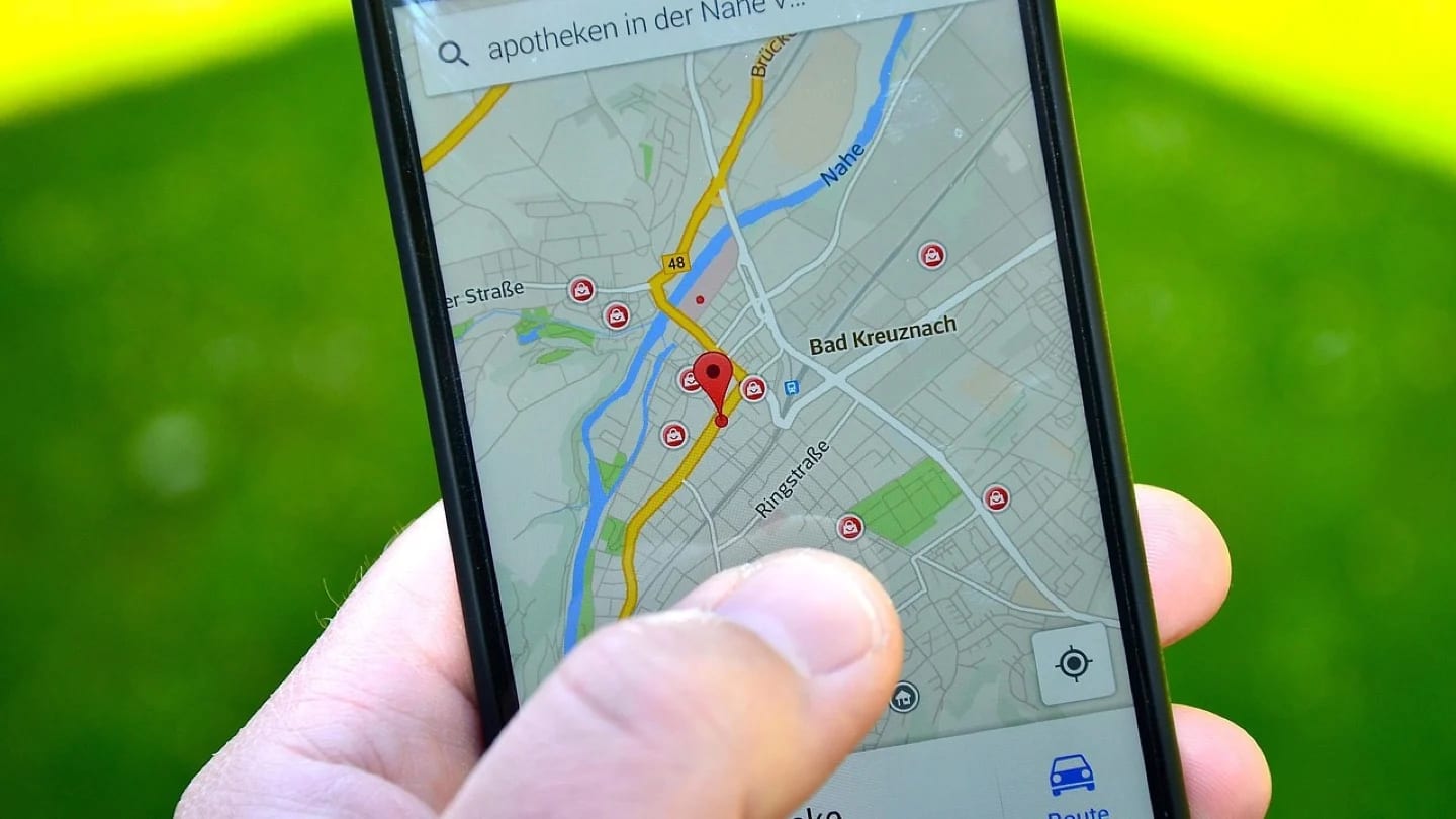 A hand holds a smartphone displaying a street map and location marker.