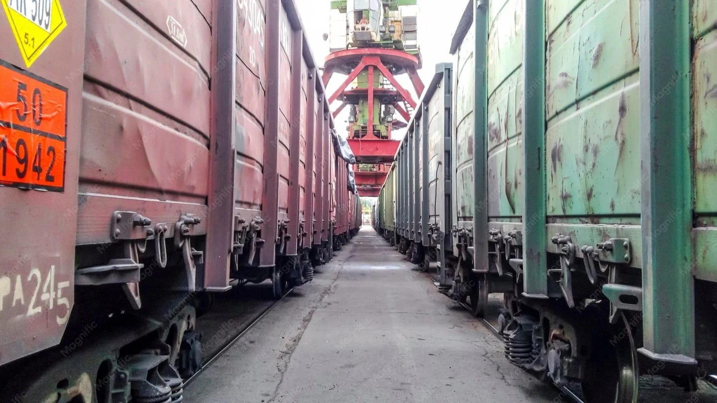 Freight rail wagons and cargo-handling equipment at a port.