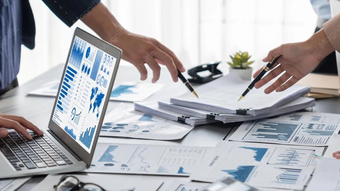 Analysts review data dashboards and project information on a laptop.