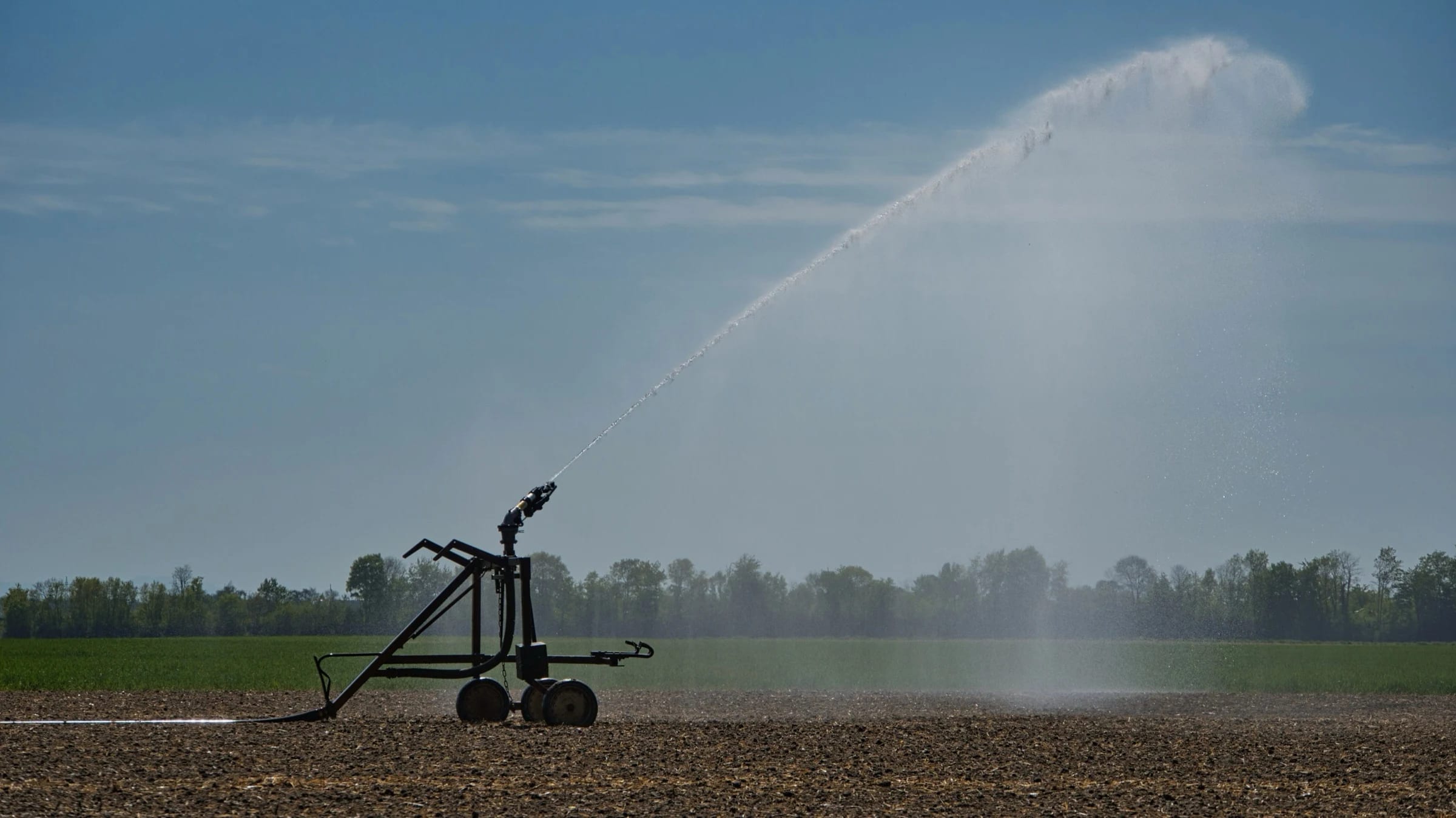 Mobile irrigation equipment spraying water across a cultivated field