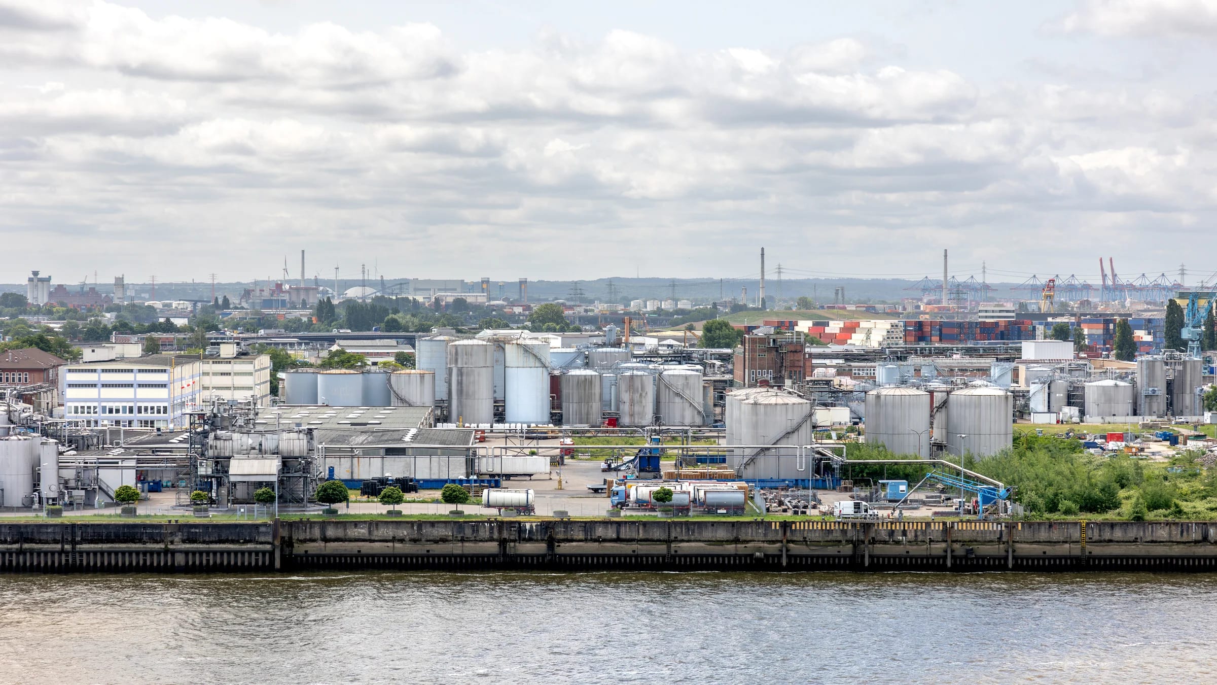 Industrial facility beside water, storage tanks and large pipework in Hamburg, Germany.