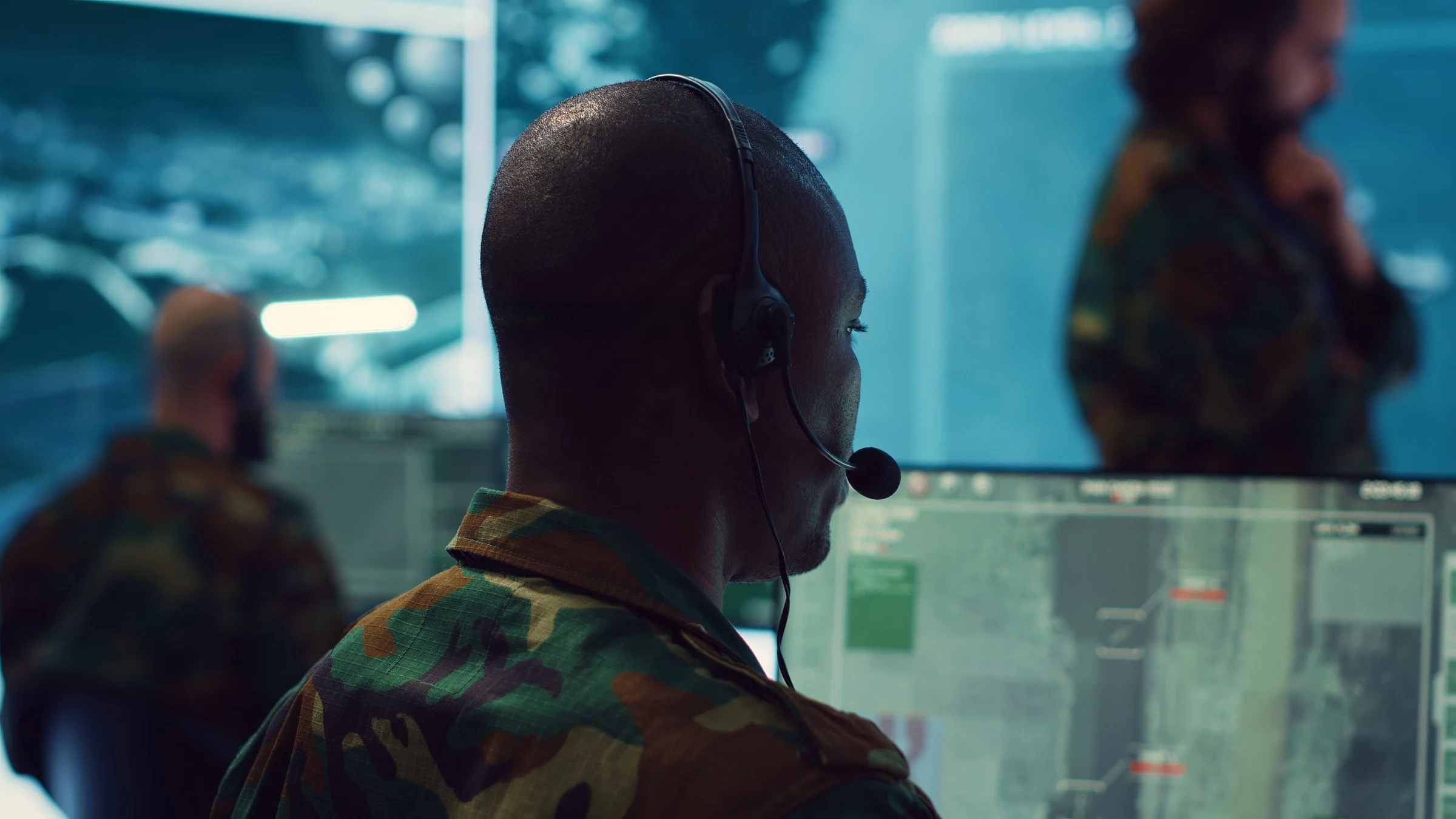 Operator wearing a headset works at a multi-screen communications desk.