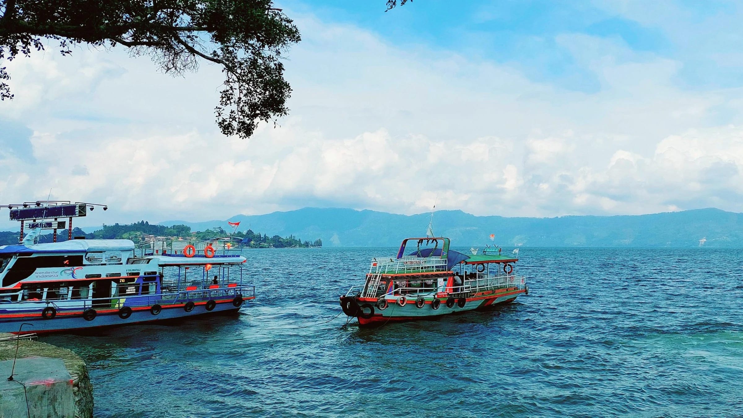 Wide view of Lake Toba and Samosir Island surrounded by green hills in North Sumatra.