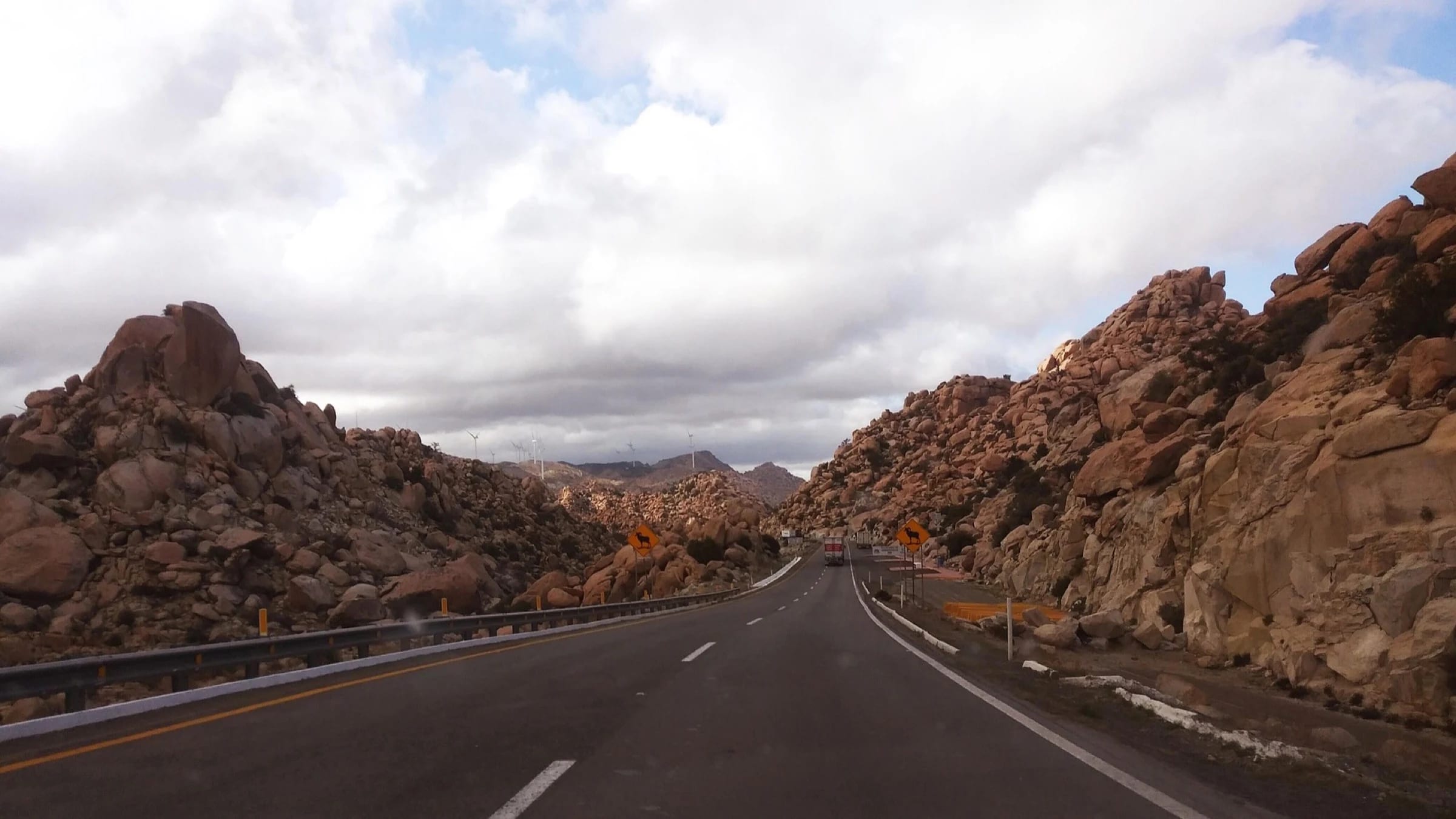 Paved road winding through dry mountainous terrain in Mexico.