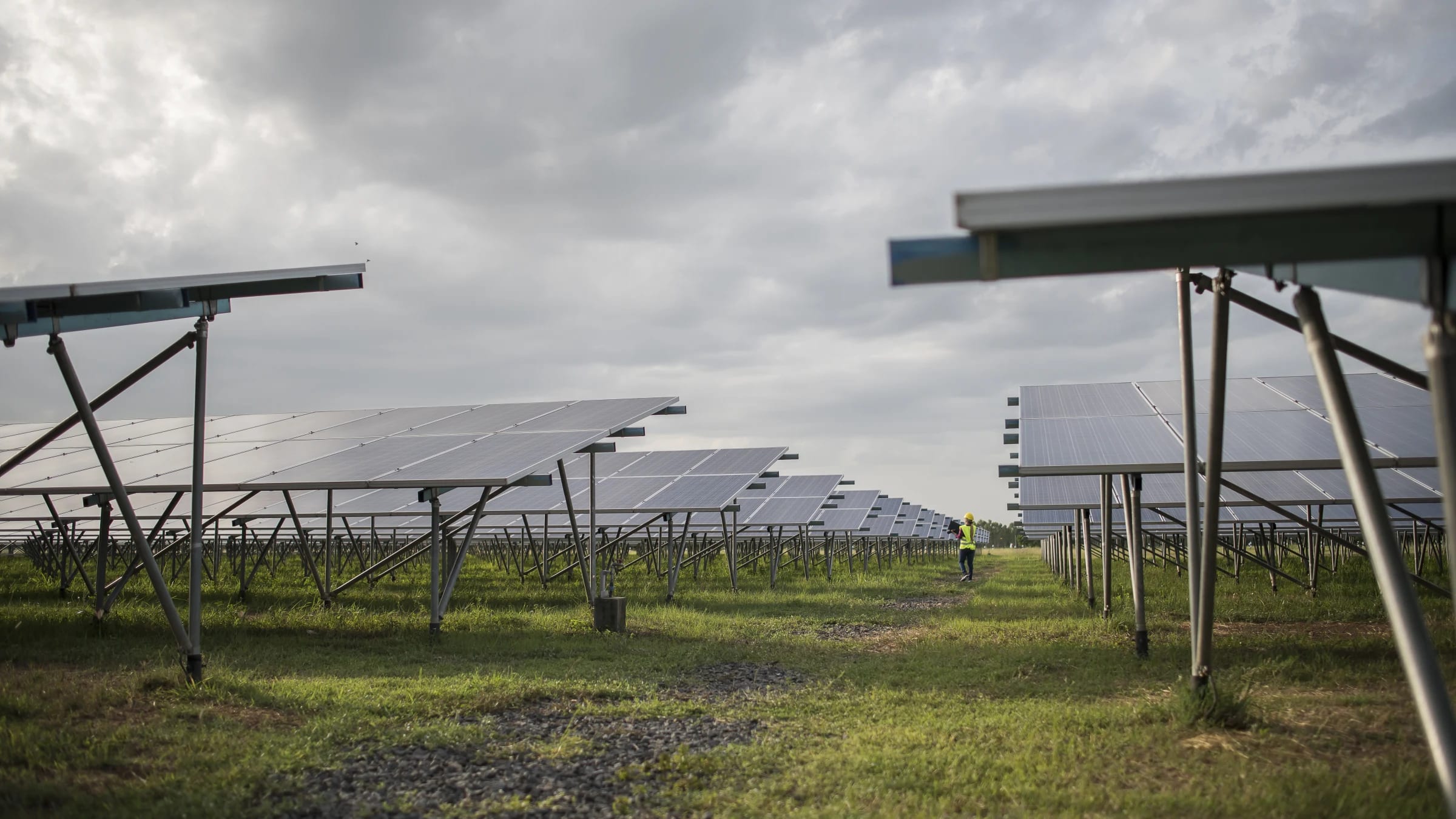 Rows of photovoltaic panels at a solar power station under open sky.
