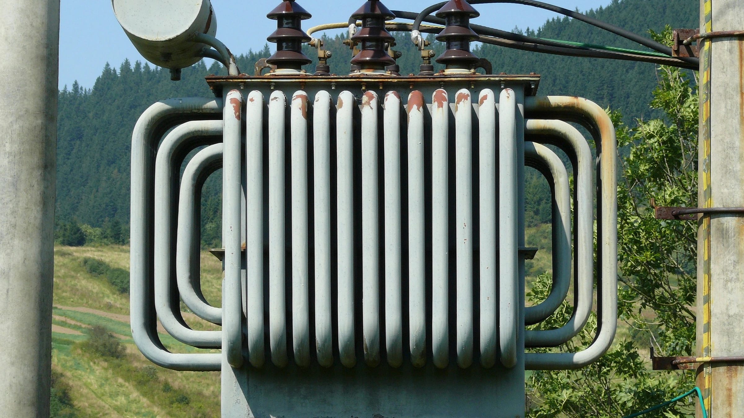 Three-phase transformer with cooling fins and electrical connections