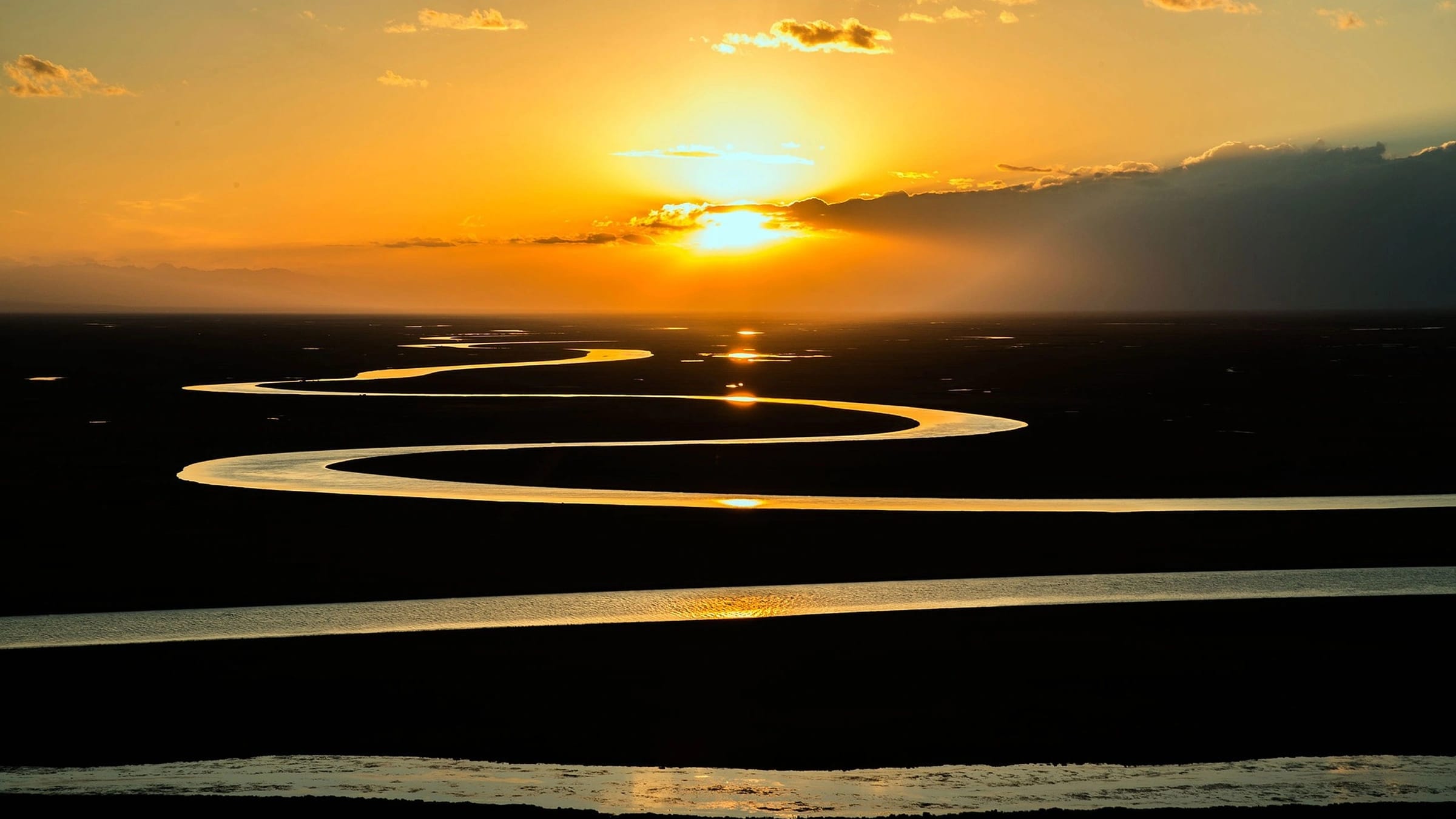 Meandering river reflecting sunset across a flat landscape