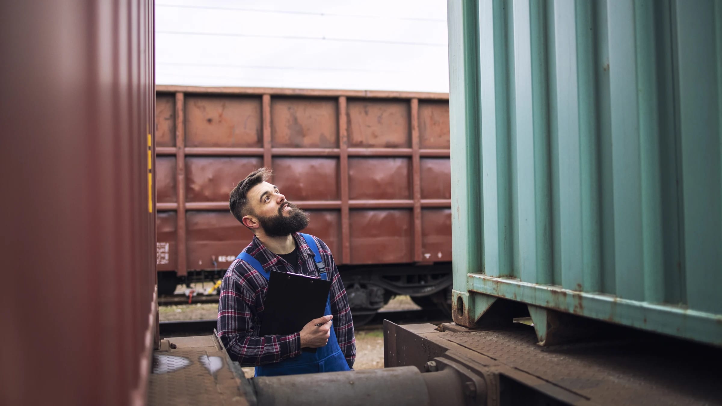Rail freight supervisor inspecting a cargo container at a train station.