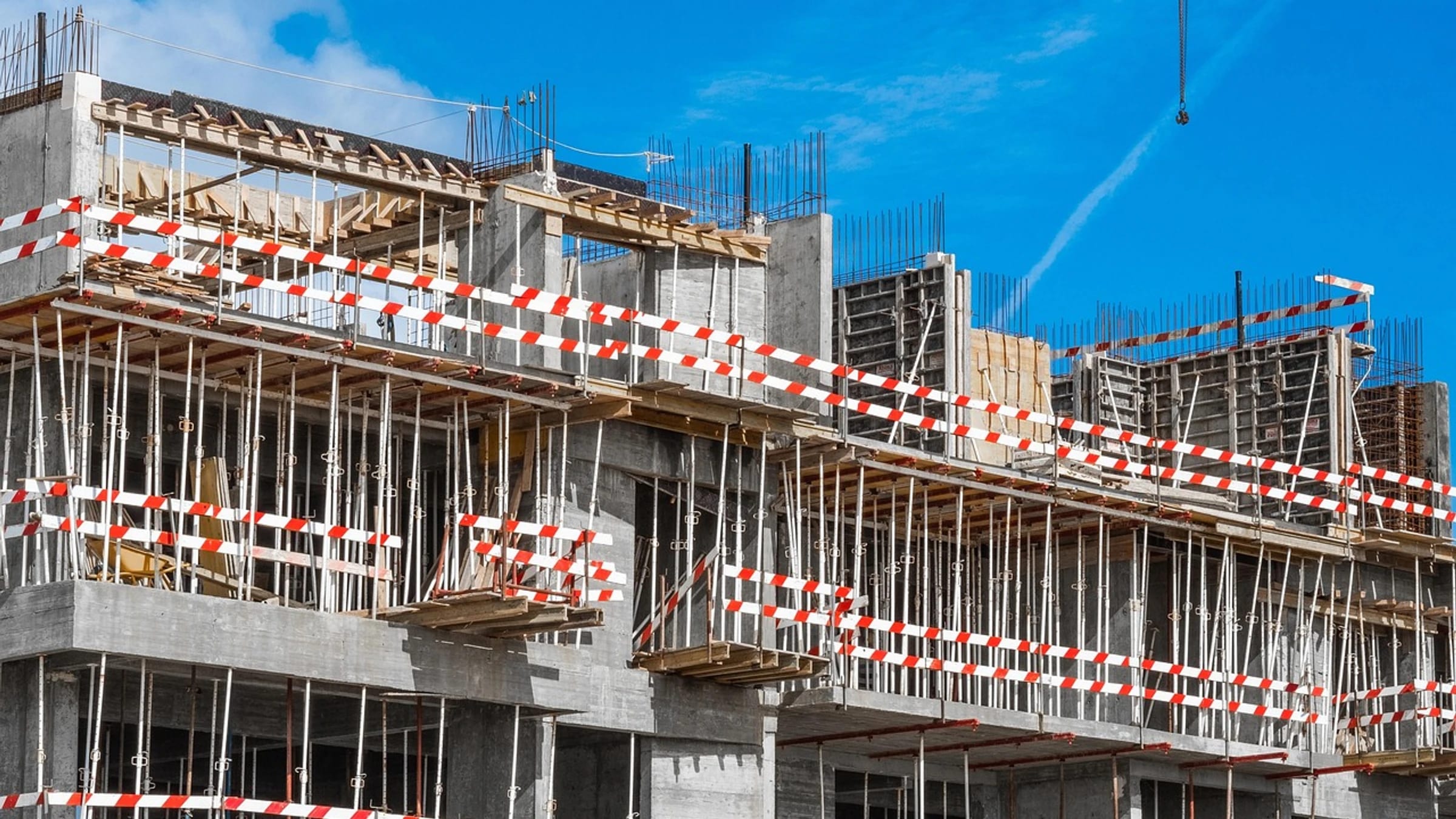 A multi-storey concrete building under construction with formwork and safety barriers.