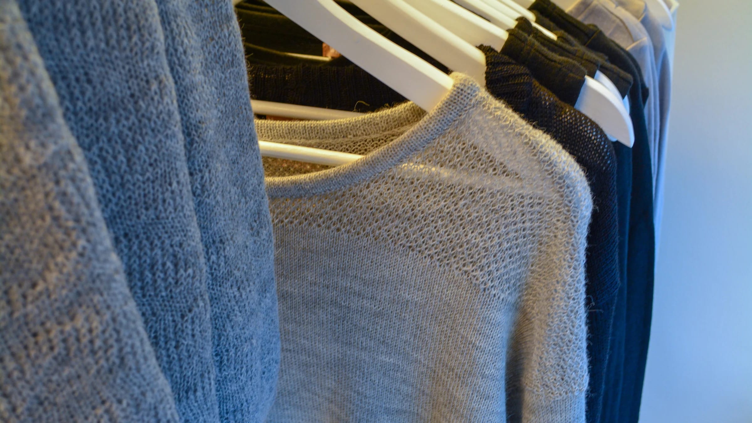 Blue garments hang closely together on a retail clothing rack.
