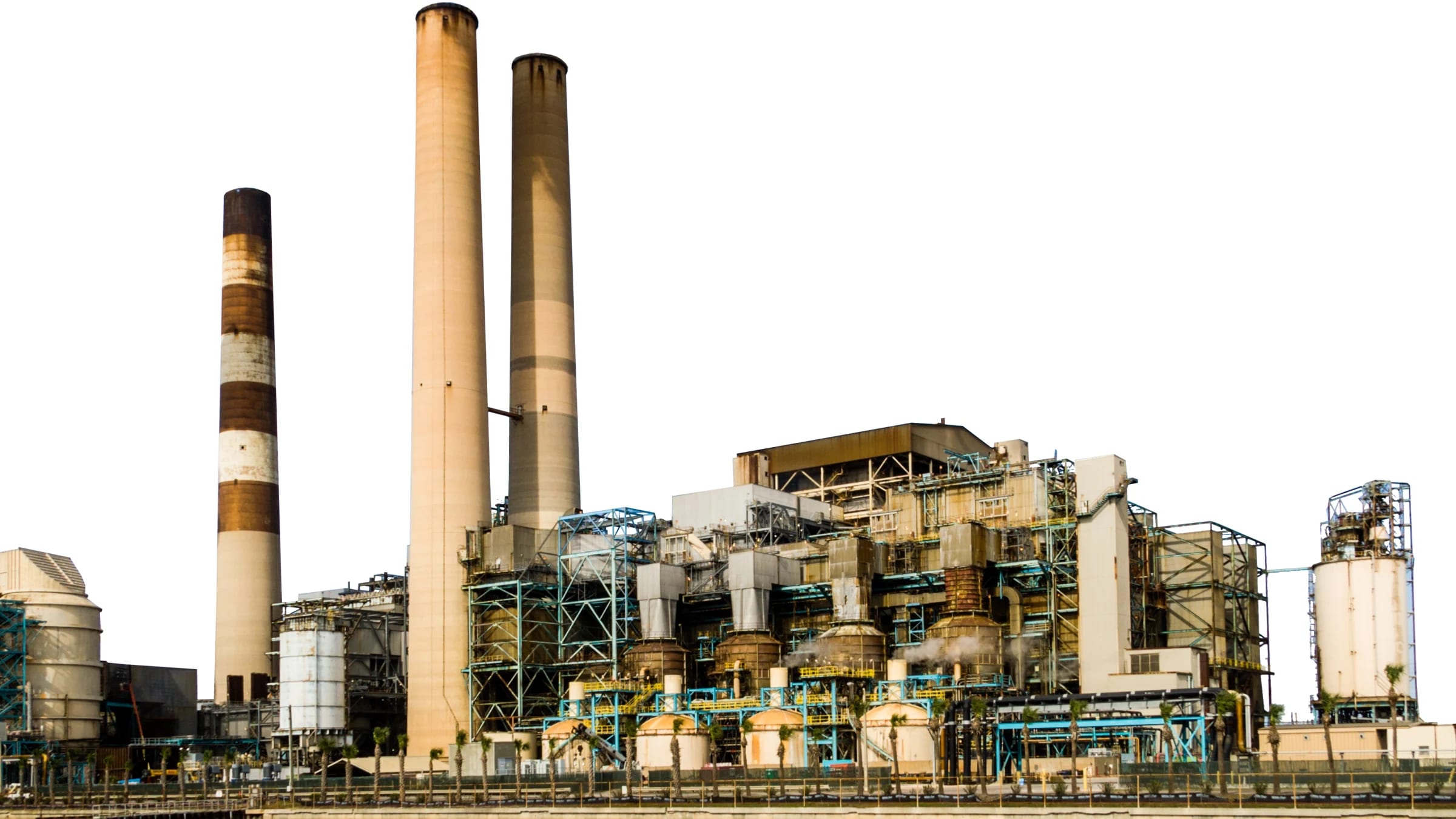 Industrial plant with pipes and smokestacks isolated against a pale sky.