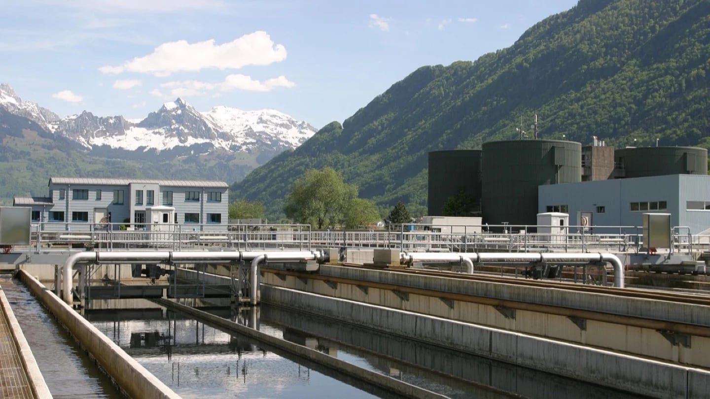 Water-treatment basins, pipes and service buildings fill a mountain-valley facility.