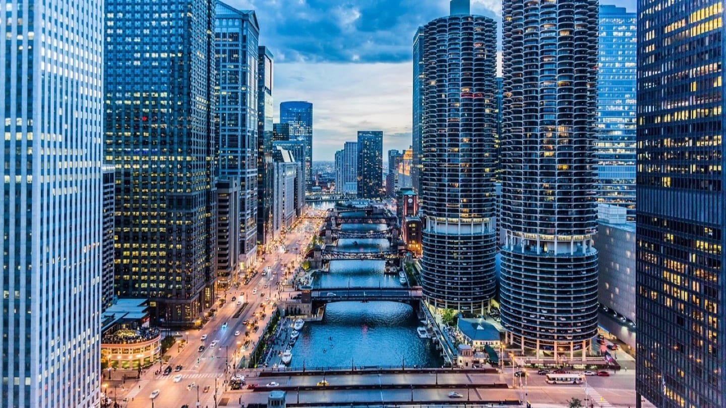High-rise buildings, bridges and a river form a dense urban infrastructure corridor at dusk.