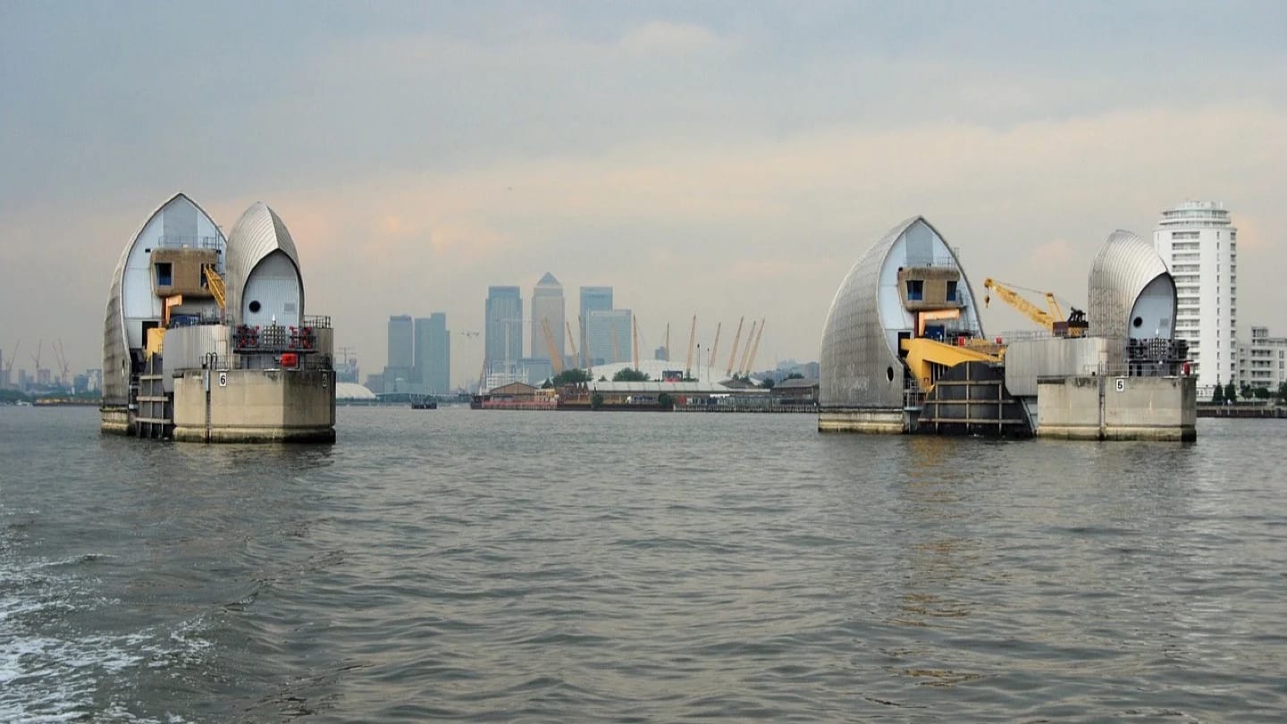 Flood-barrier gates stand in the River Thames with the London skyline beyond.
