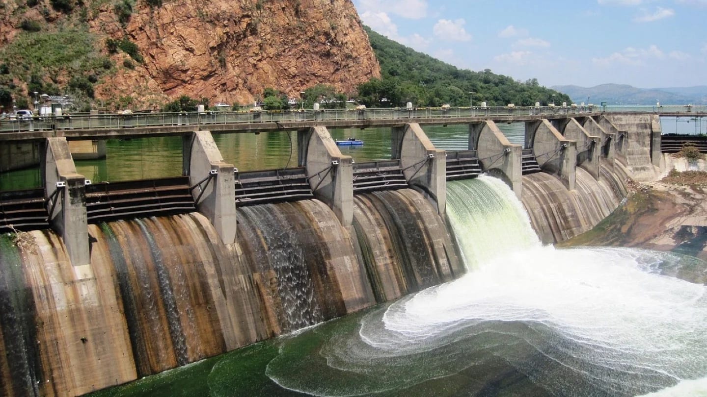 A concrete dam releases water through several sluice gates.