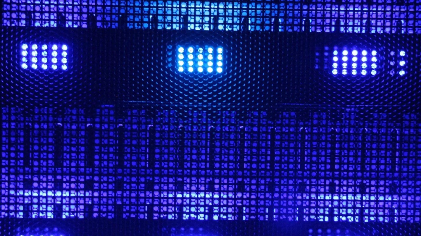 Blue lights glow behind the perforated grille of data-center hardware.