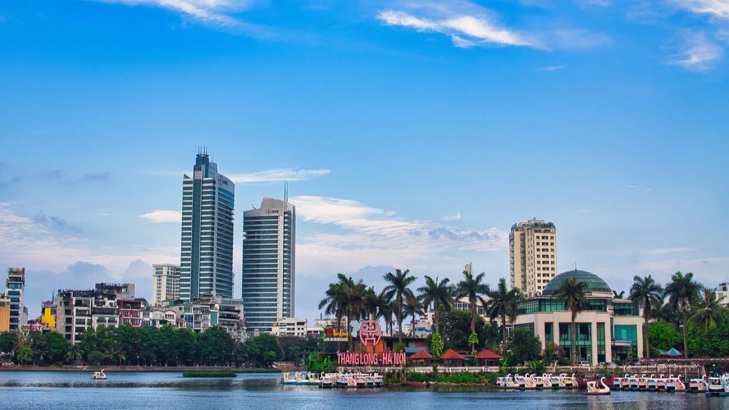Hanoi’s urban skyline and waterfront appear under a clear blue sky.