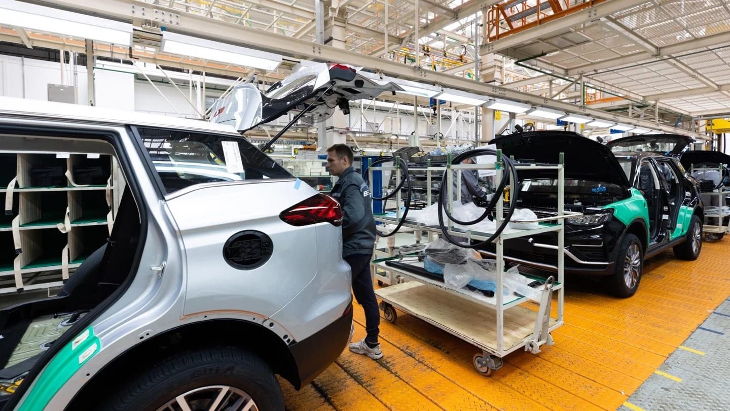 Workers assemble vehicles on a modern automotive production line.