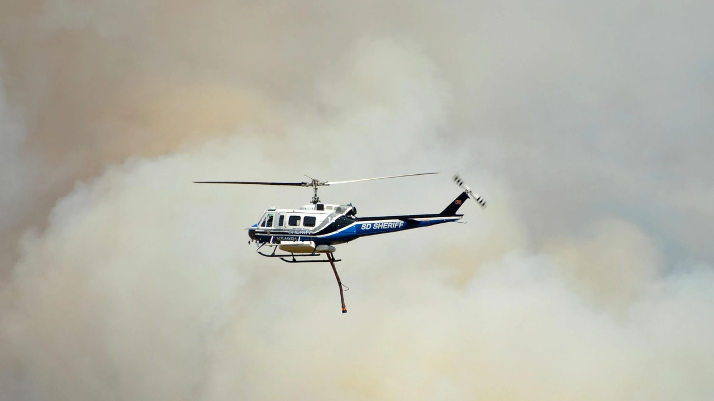 A helicopter flying through smoke during a wildfire response.