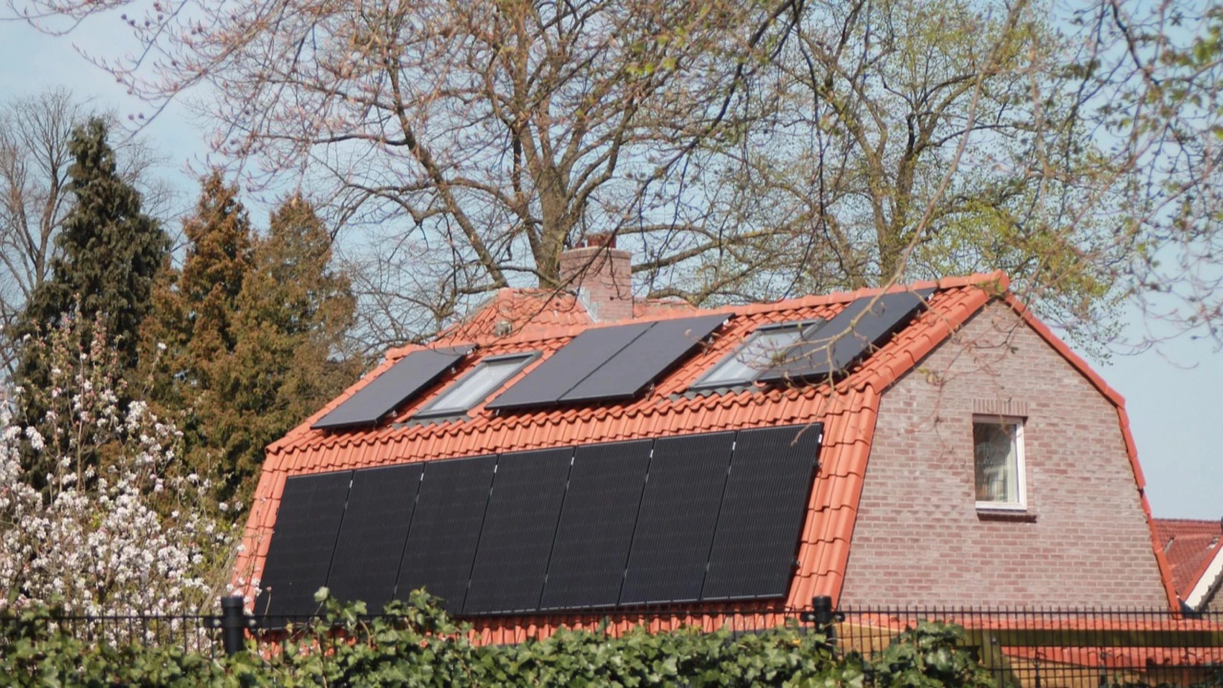 Solar panels mounted across the tiled roof and upper wall of a home.