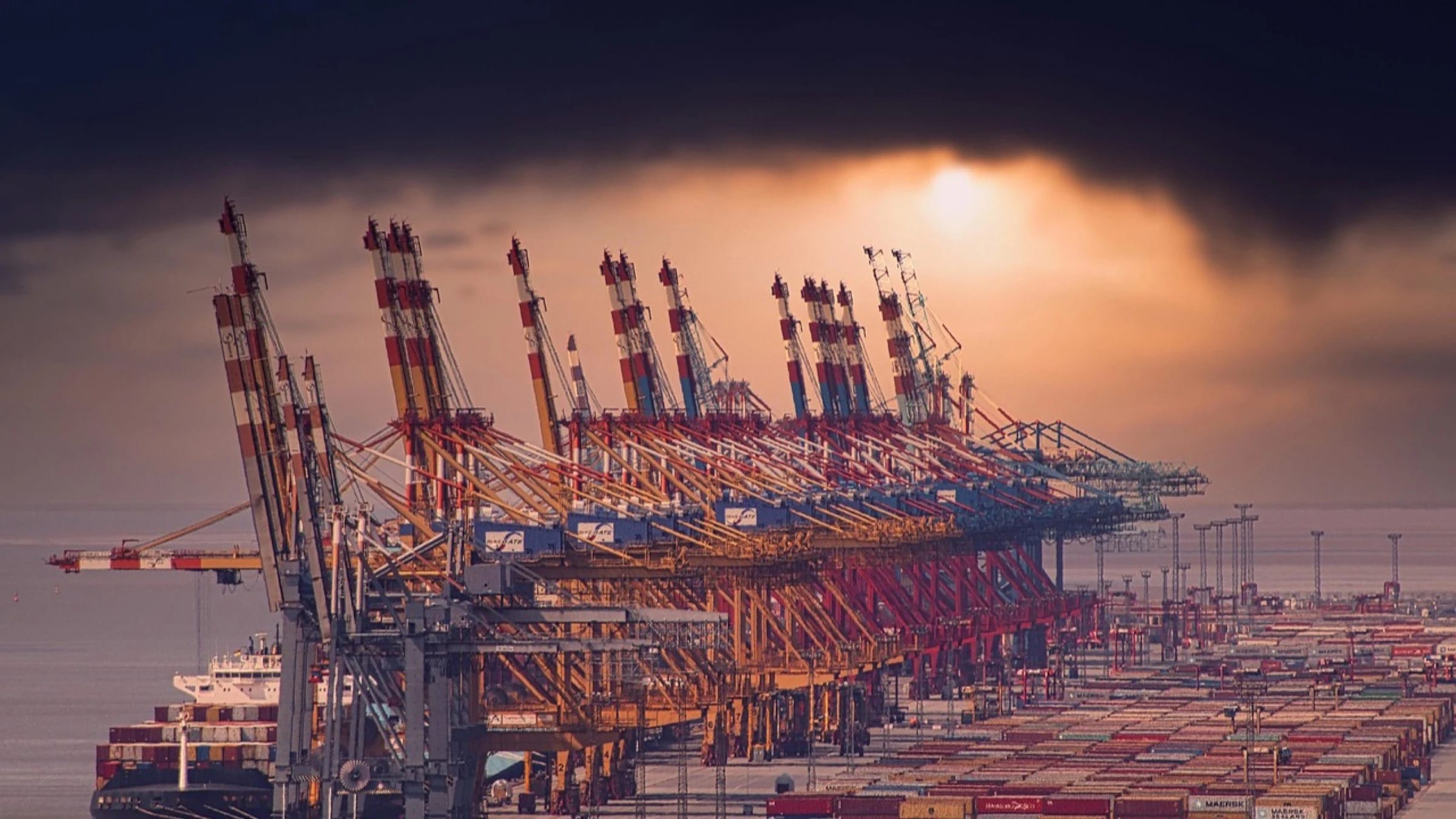 Container cranes and a cargo ship at a large waterside port.