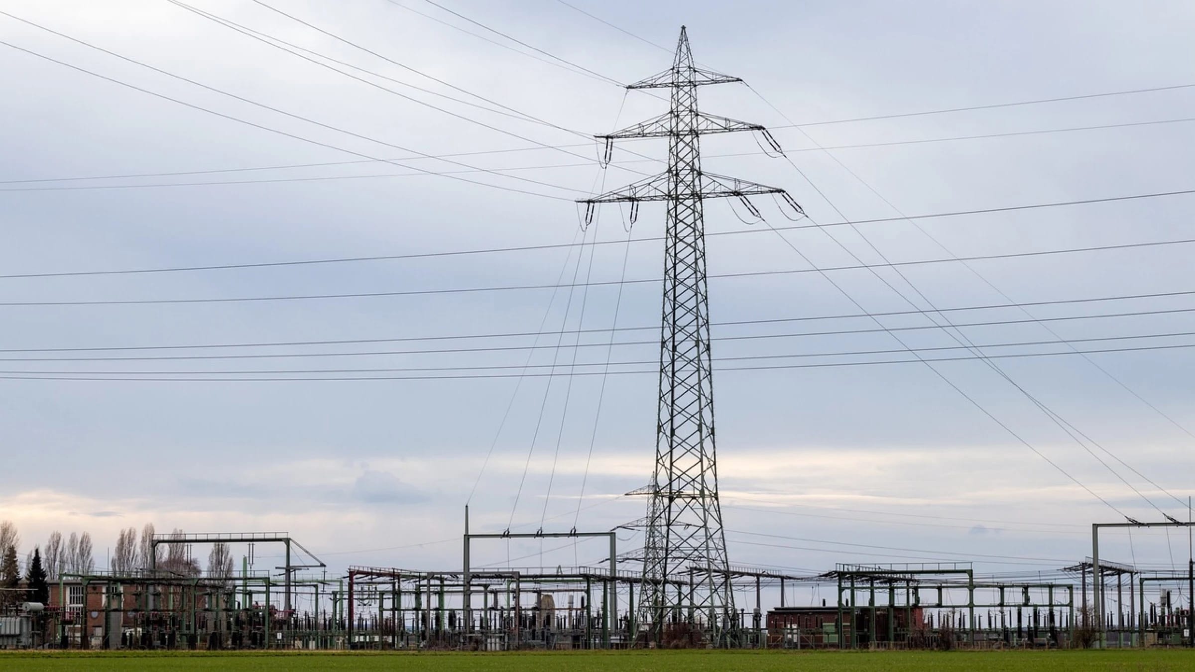 Electrical substation equipment beneath a high-voltage transmission tower.