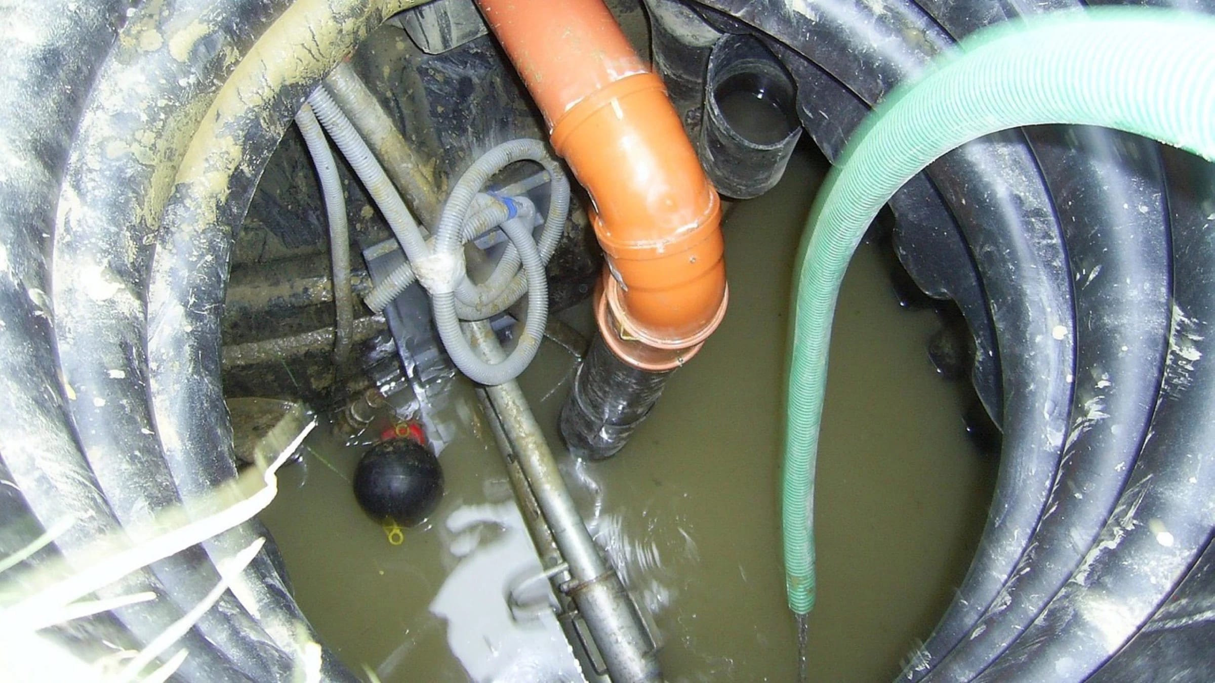 Pipes and a ladder inside an open sewer chamber.
