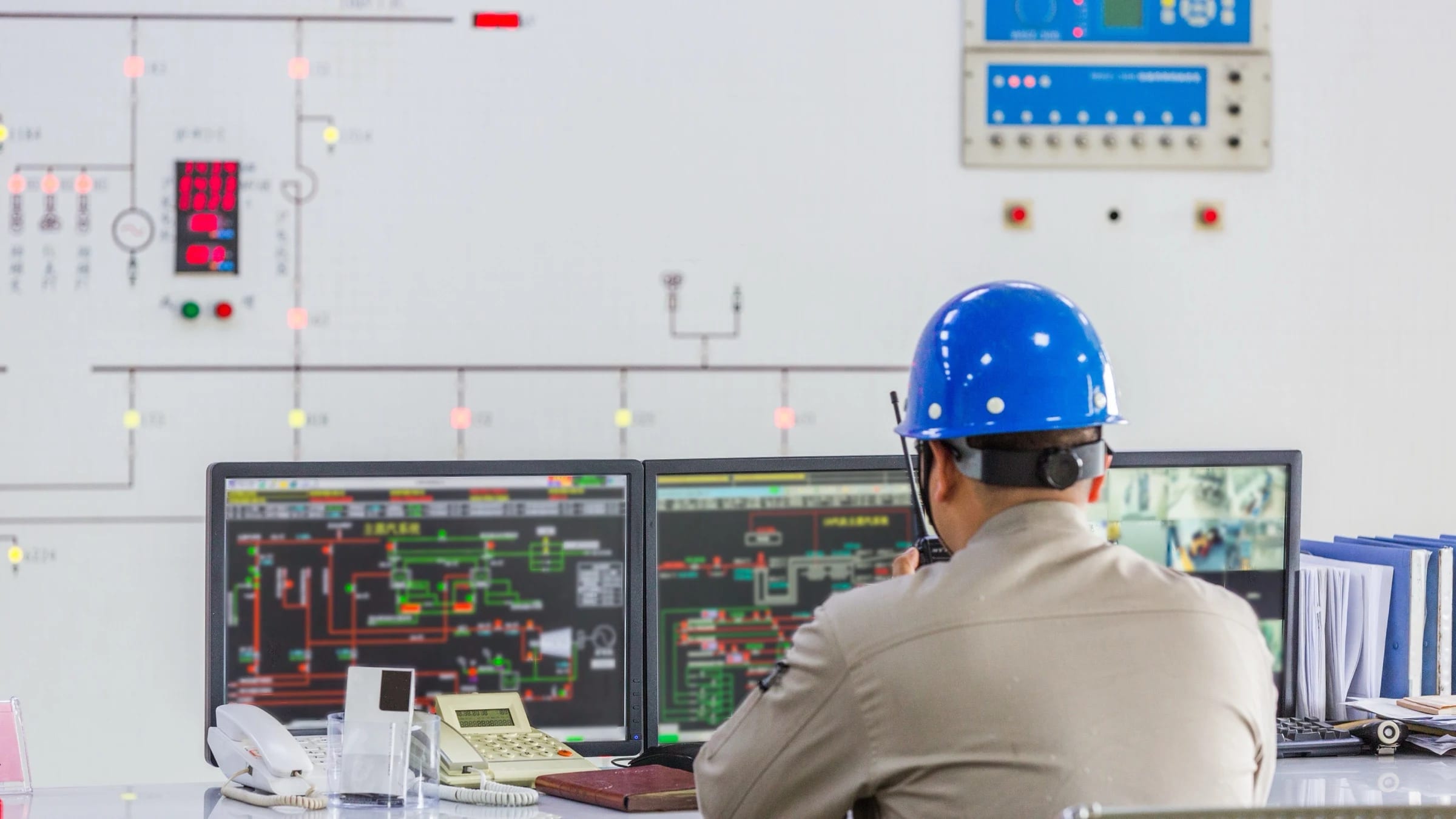 An electricity-system operator monitors control screens in a grid control room.