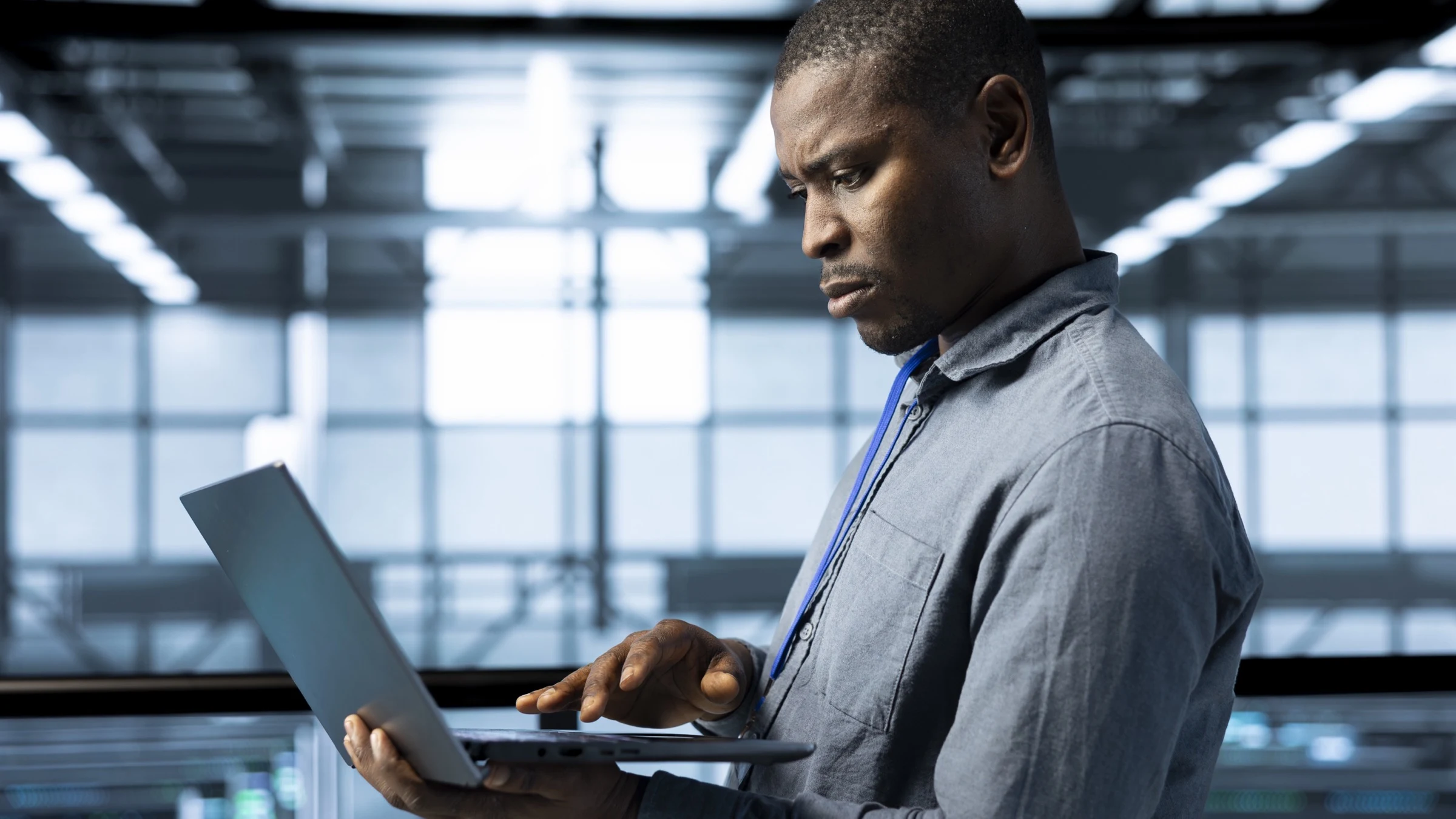 A data-centre technician uses a laptop beside server equipment.