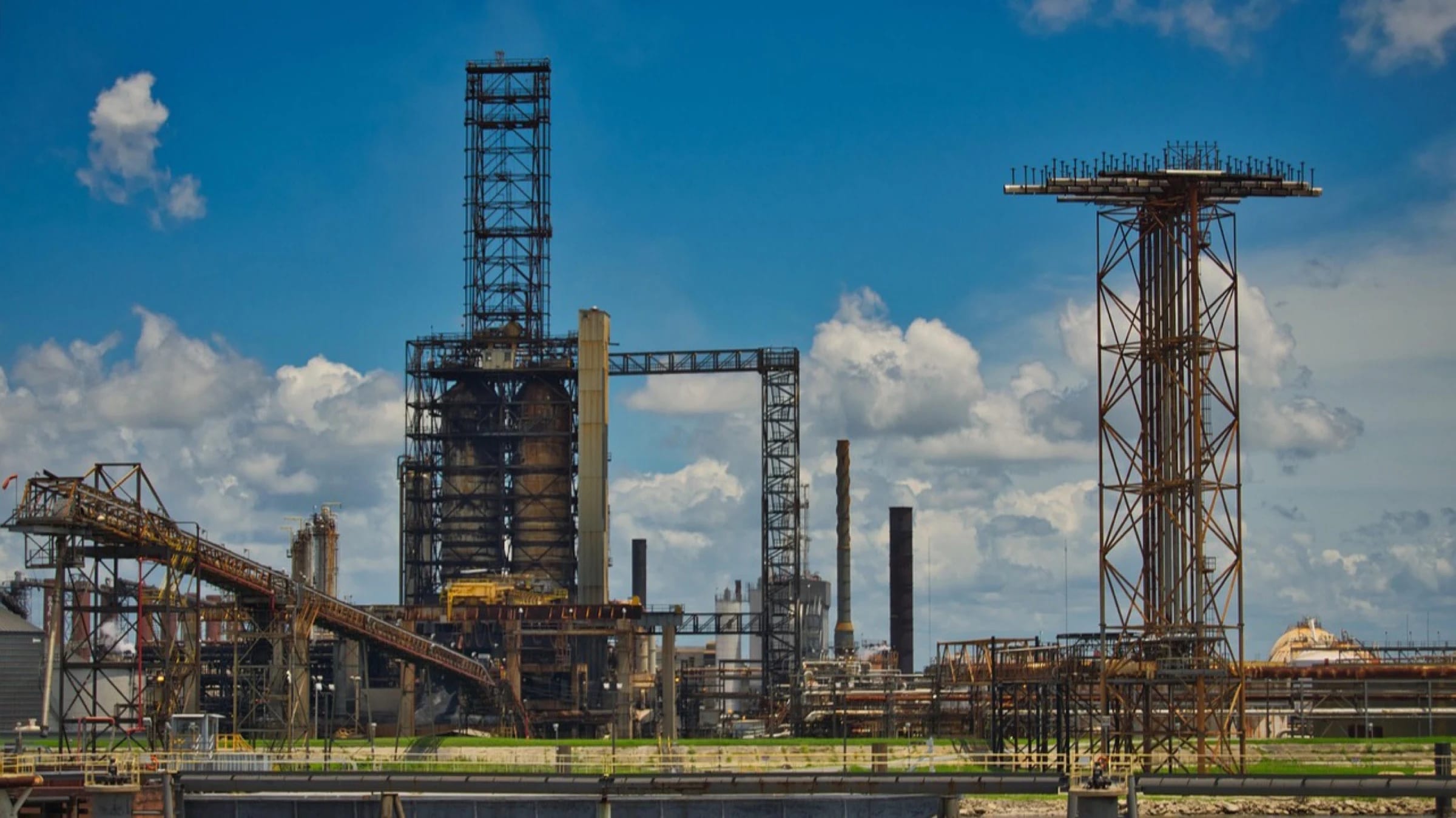 Dense industrial pipework and processing towers at an oil refinery.