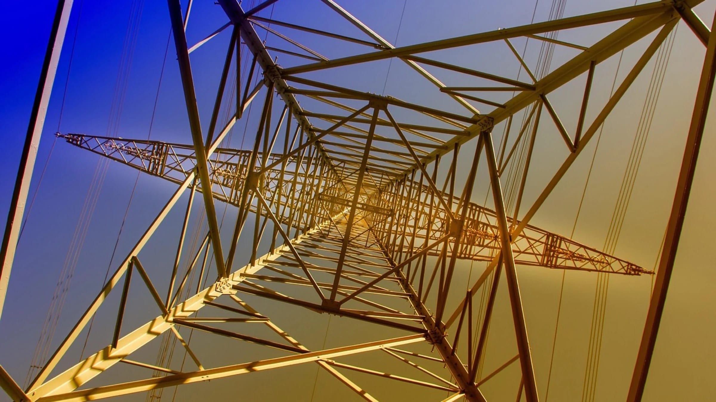 High-voltage transmission tower and power lines against a clear sky.