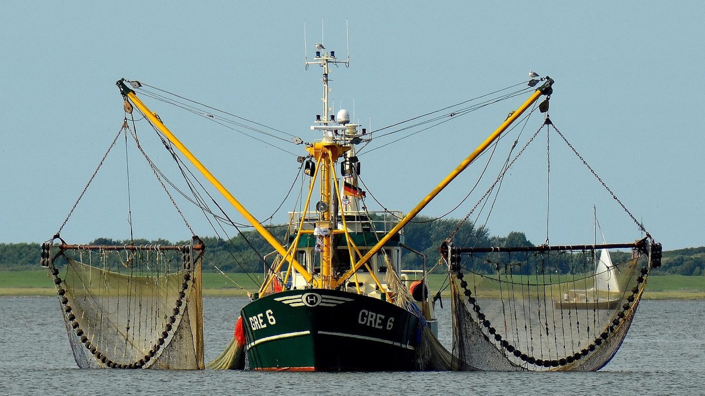 Commercial fishing vessel with nets extended on both sides.