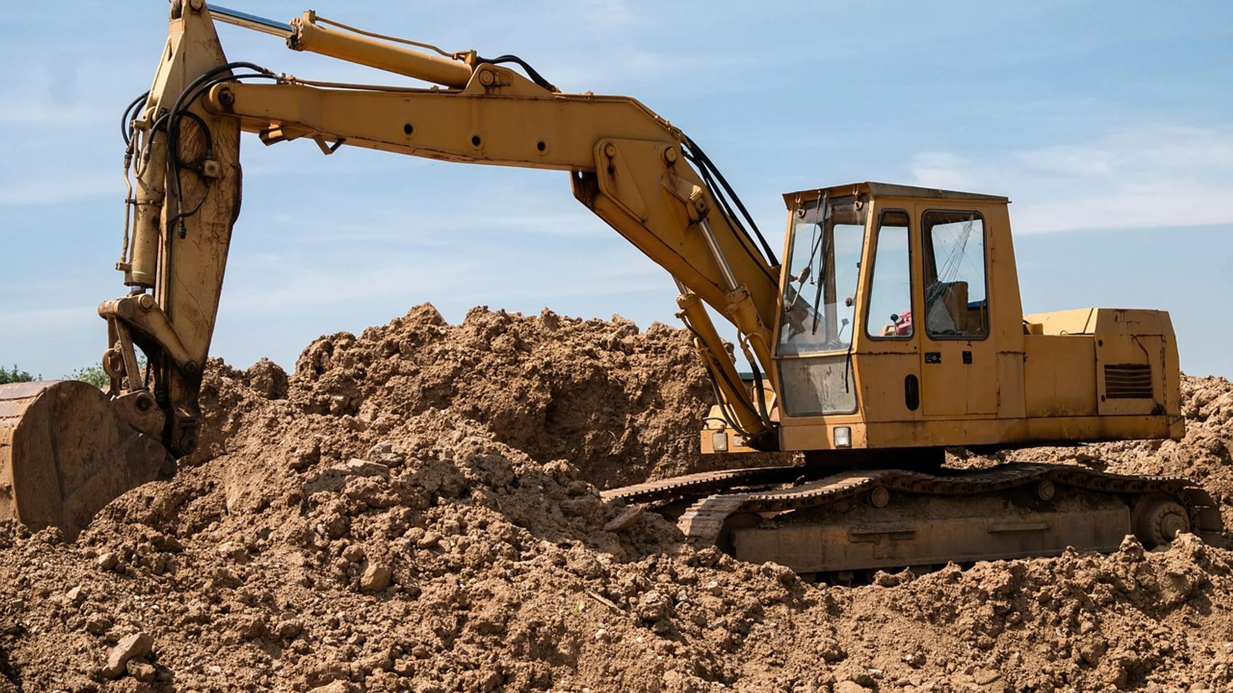 Excavator working on a large construction site beneath an open sky.