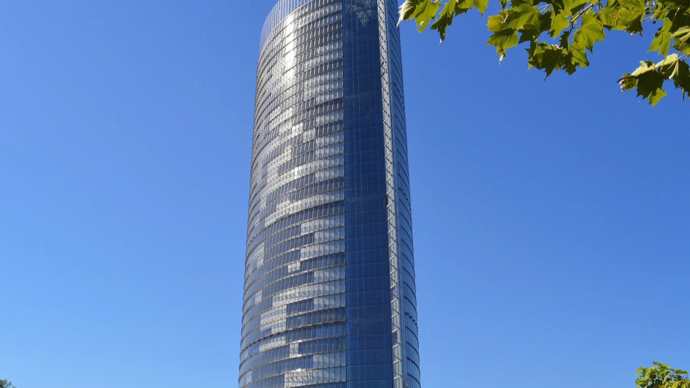 A tall glass communications tower against a clear blue sky.