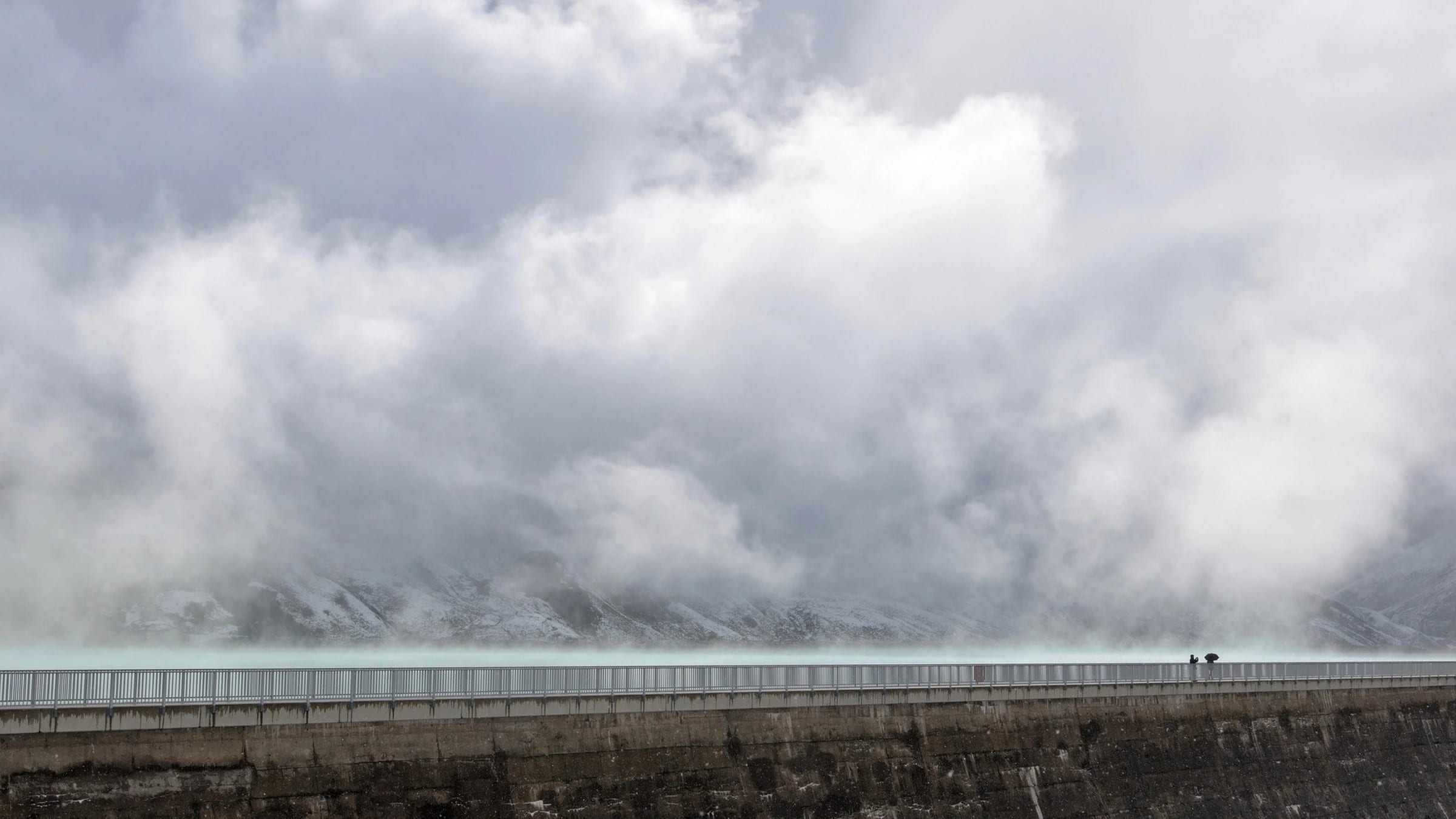 Reservoir and dam wall beneath clouds in an alpine landscape