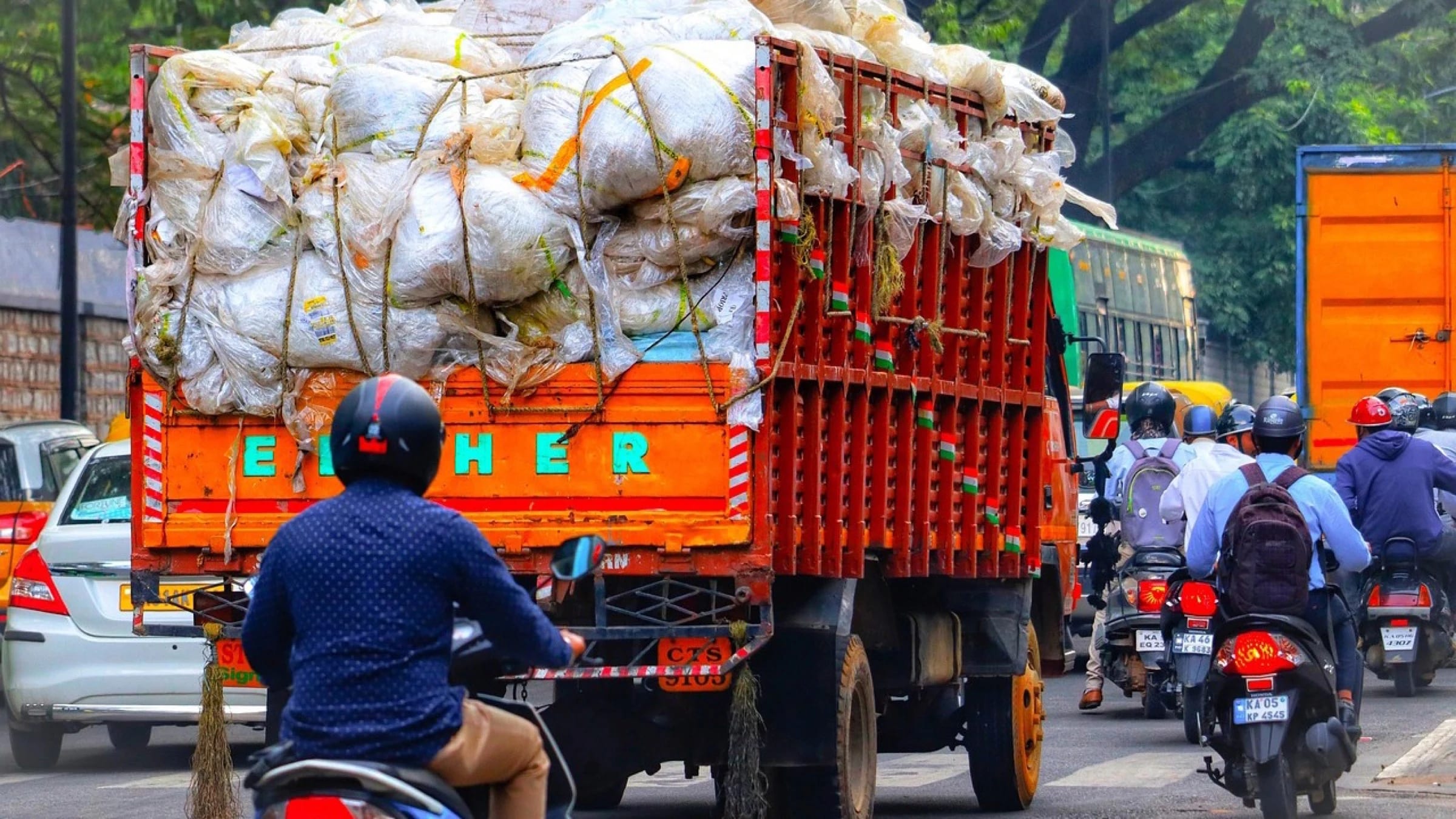 Truck carrying bags of collected material on a busy street