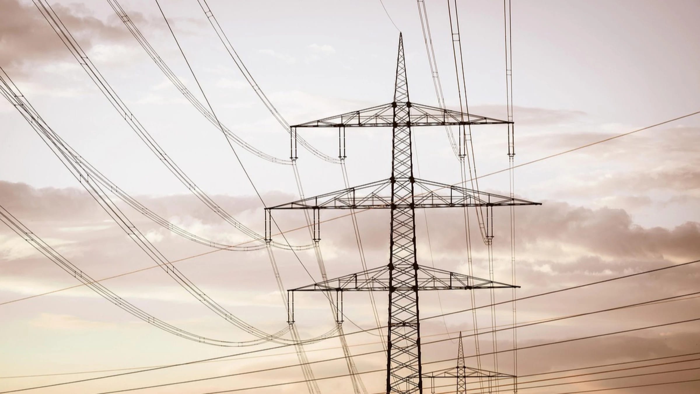 Power lines and electricity pylons against a cloudy sky.