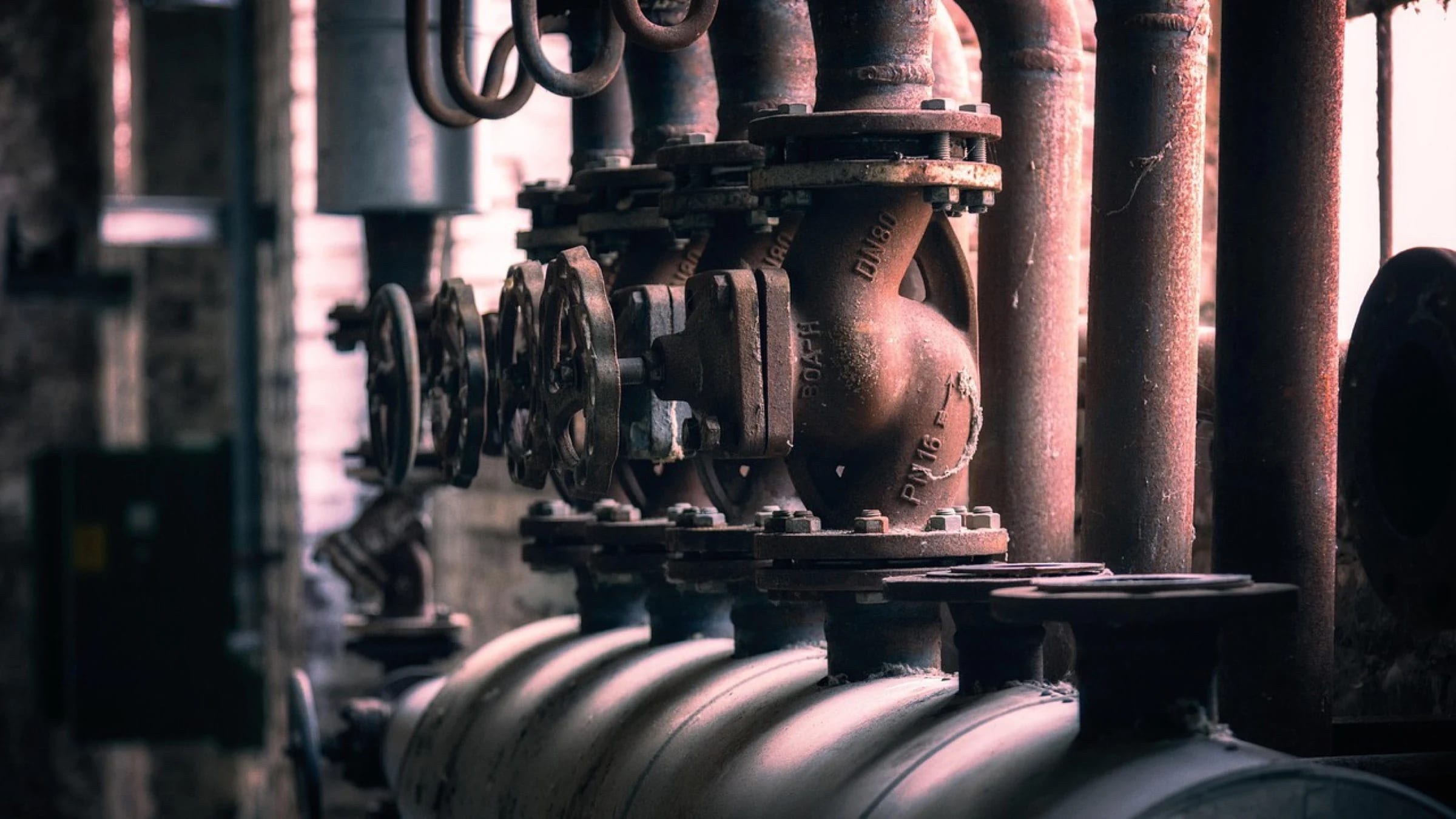 Industrial pipes and a large valve inside a plant.