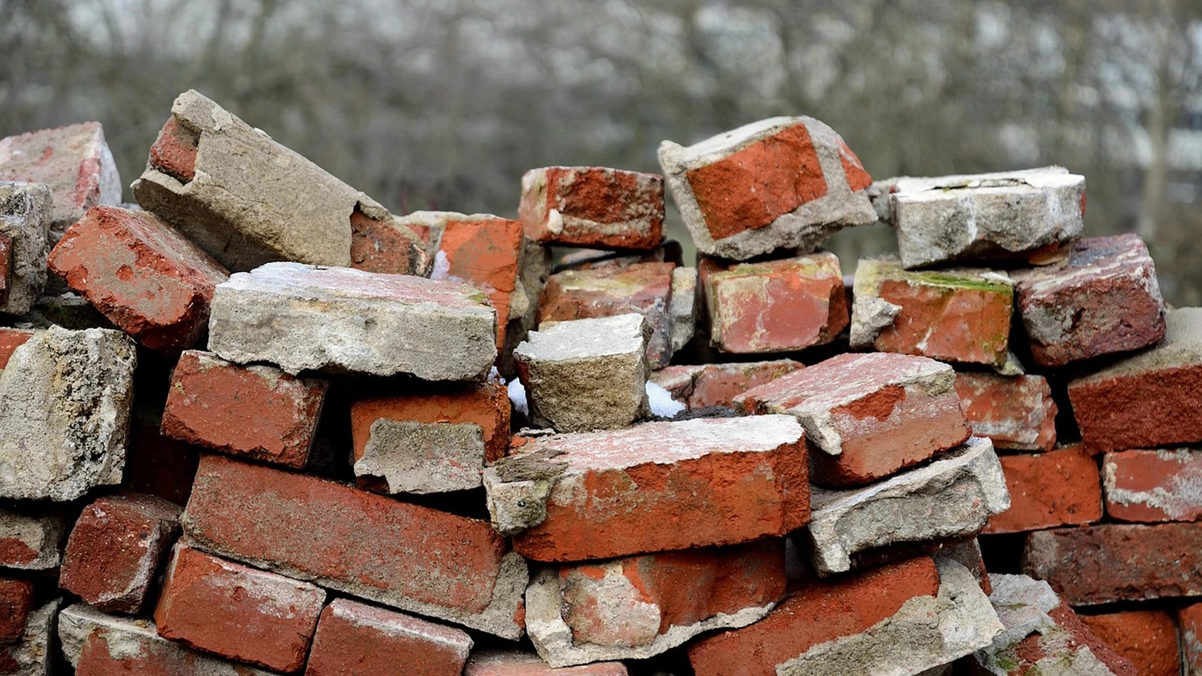 A pile of red and pale bricks with mortar residues.