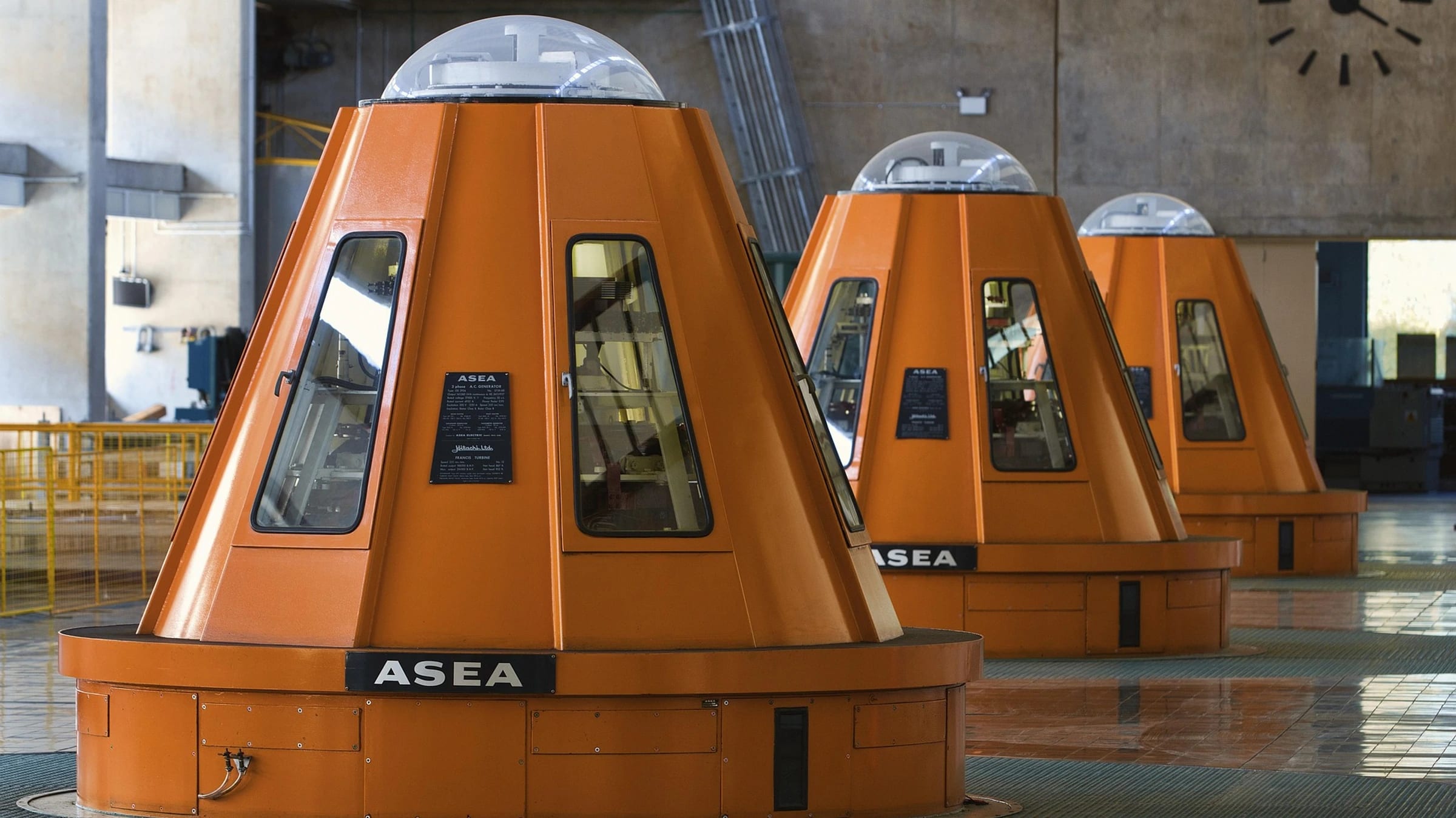 Orange generator housings inside a hydropower facility.