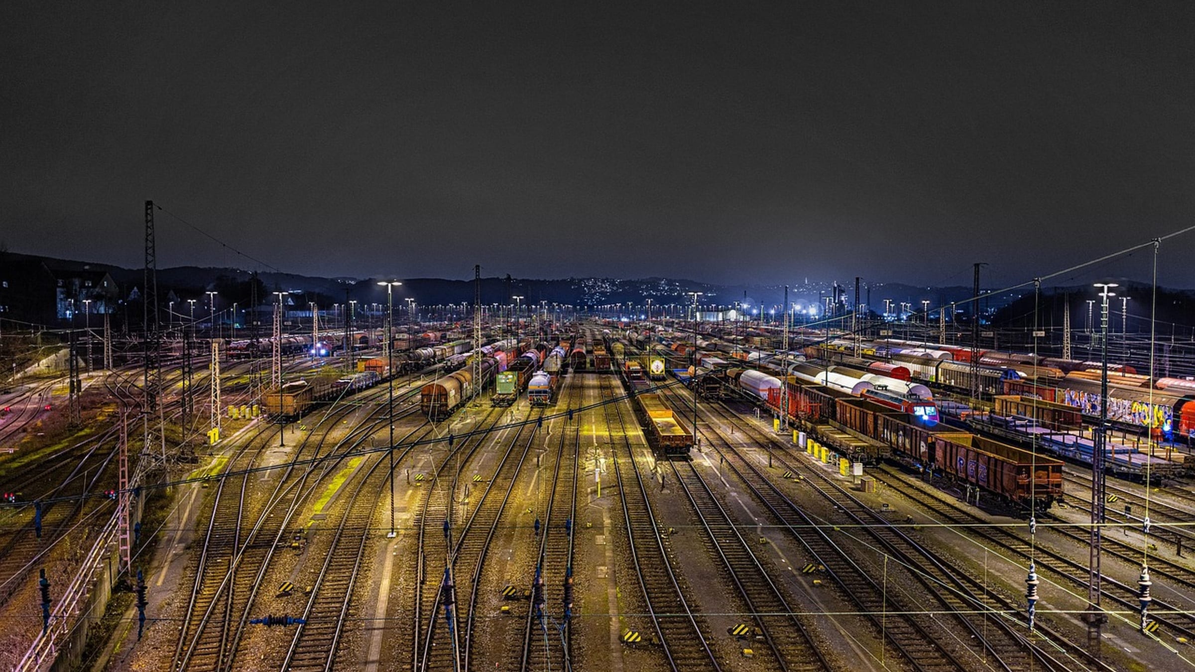 Parallel tracks and freight trains in a railway depot at night.
