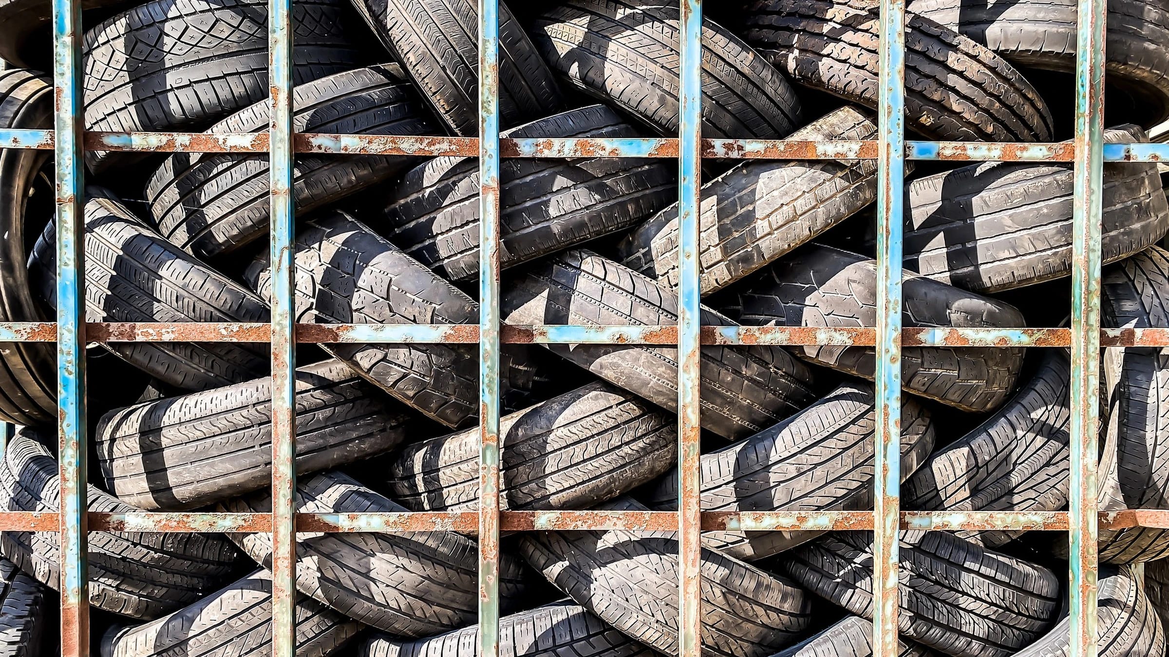Used vehicle tyres stacked inside a fenced storage area.