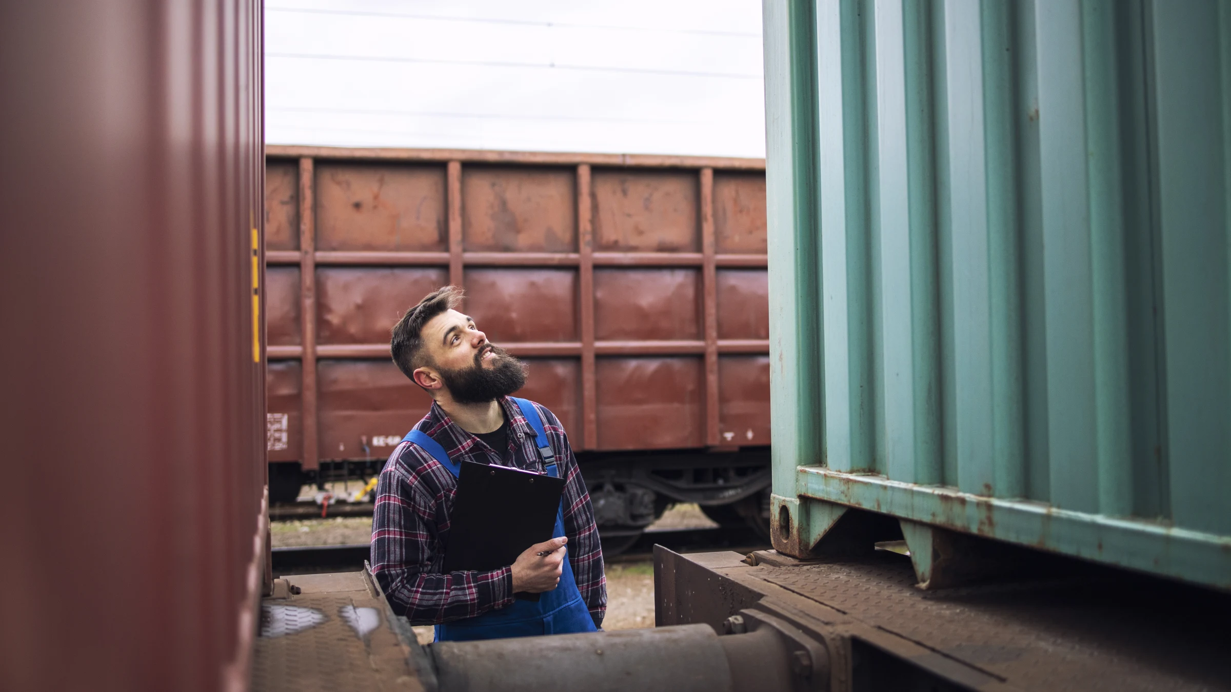Rail freight supervisor inspecting a cargo container at a train station.