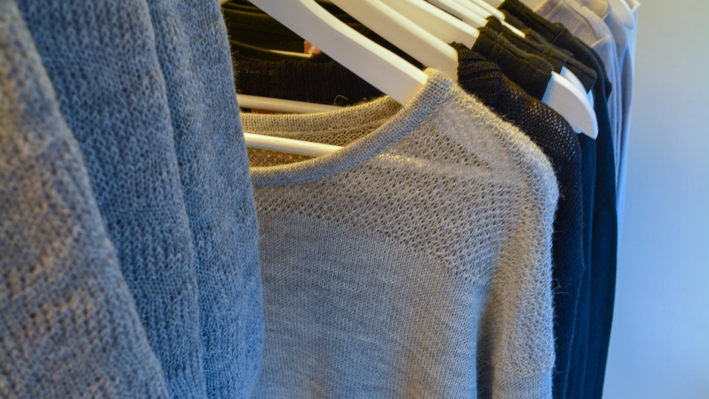 Blue garments hang closely together on a retail clothing rack.