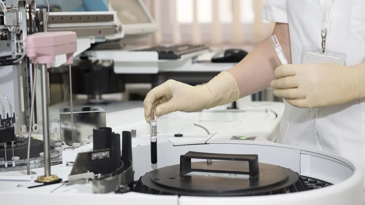 A medical professional loads blood samples into automated diagnostic laboratory equipment.