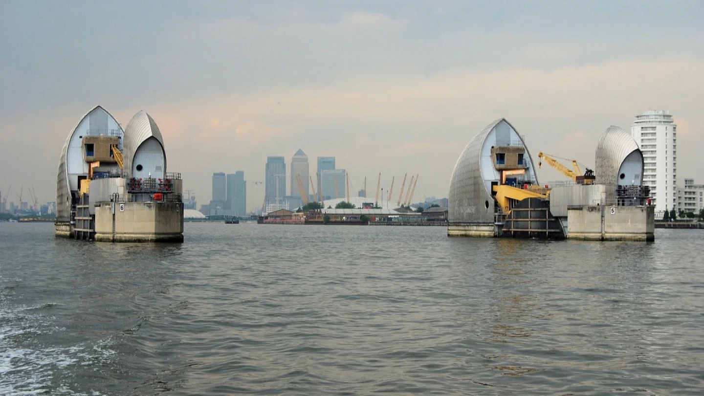 Flood-barrier gates stand in the River Thames with the London skyline beyond.