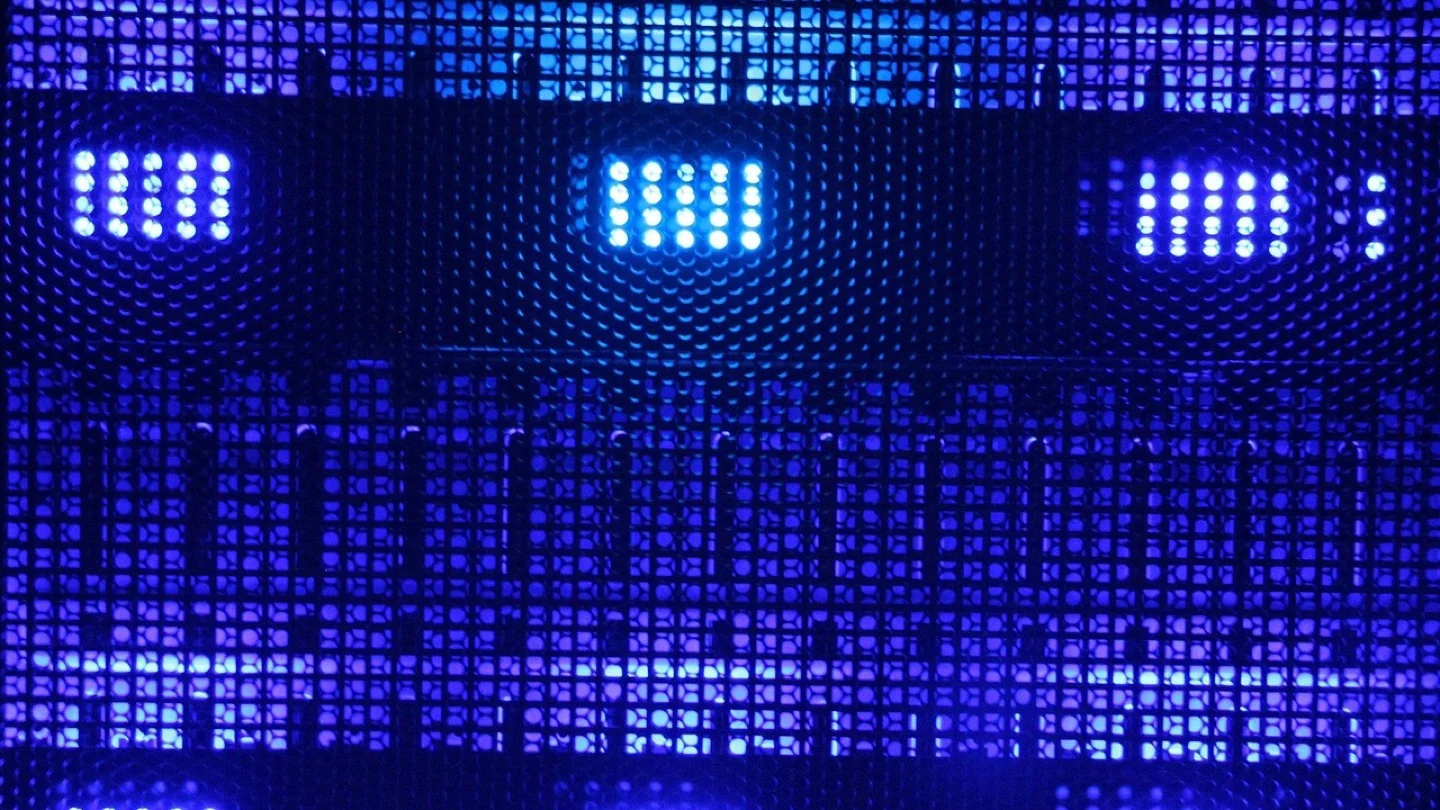 Blue lights glow behind the perforated grille of data-center hardware.