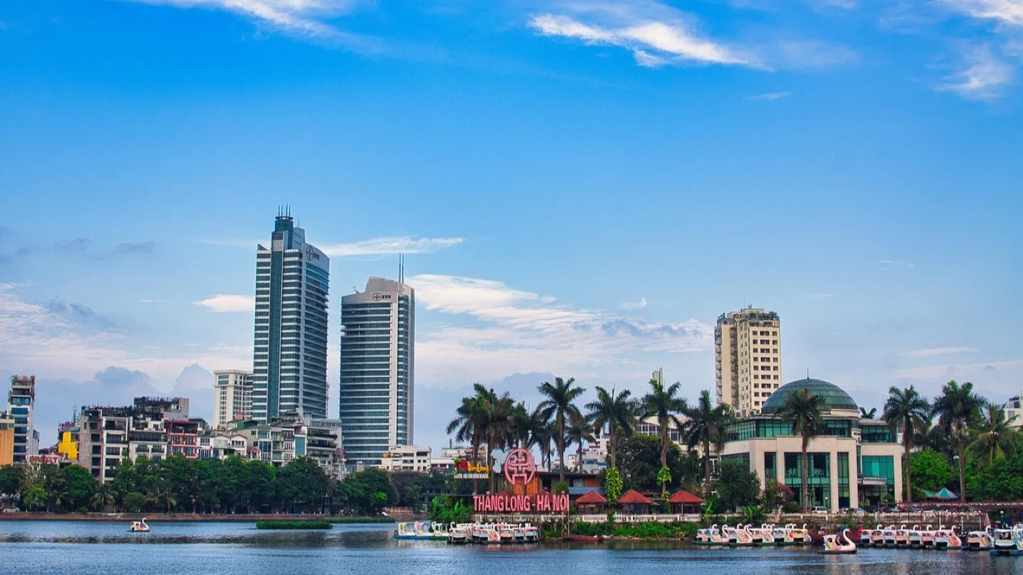 Hanoi’s urban skyline and waterfront appear under a clear blue sky.