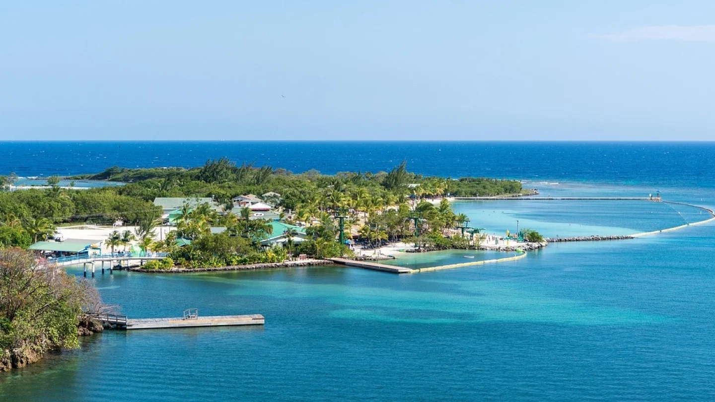 A Caribbean island settlement and harbor sit beside clear blue water.